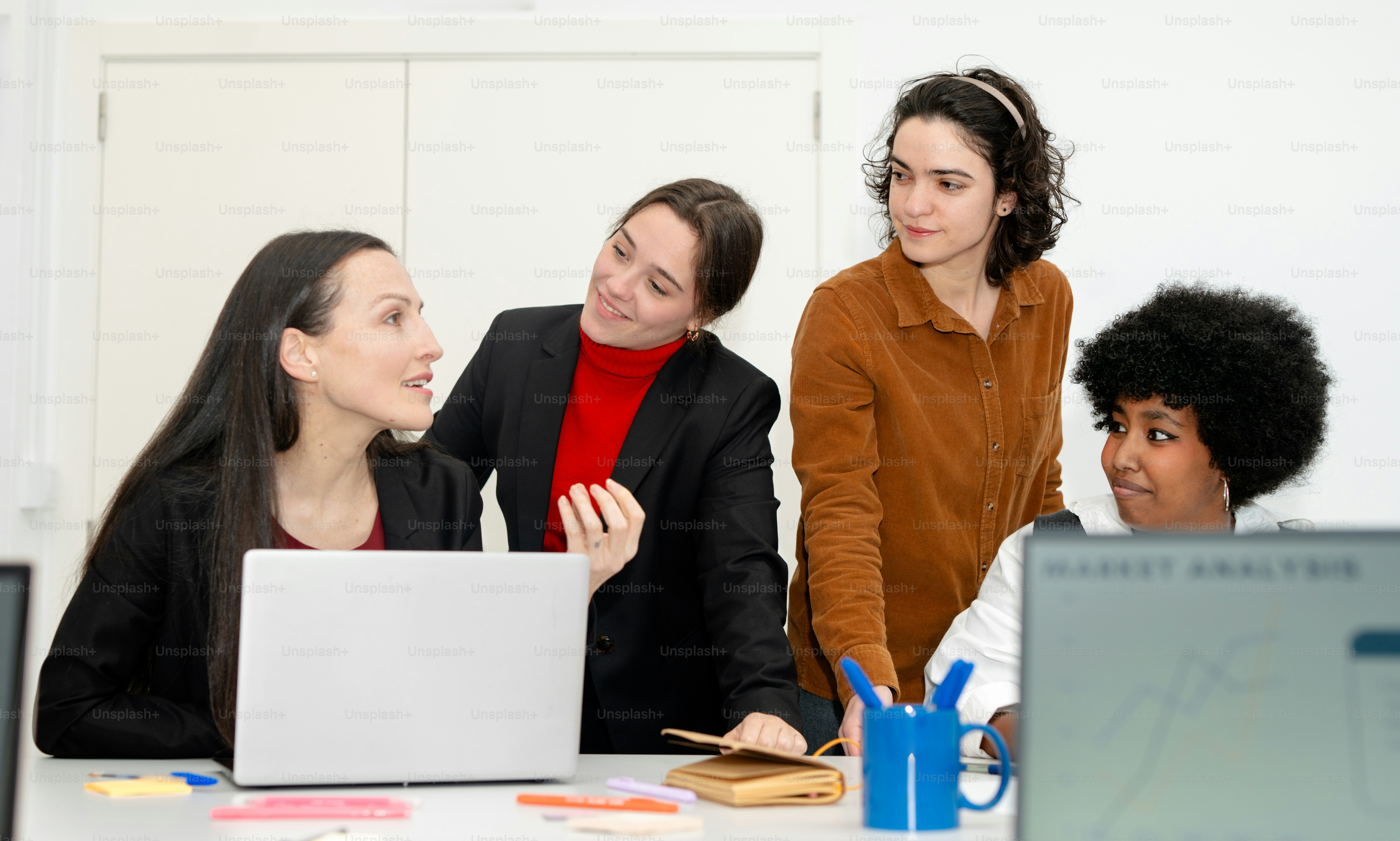A group of people sitting around a table with laptops