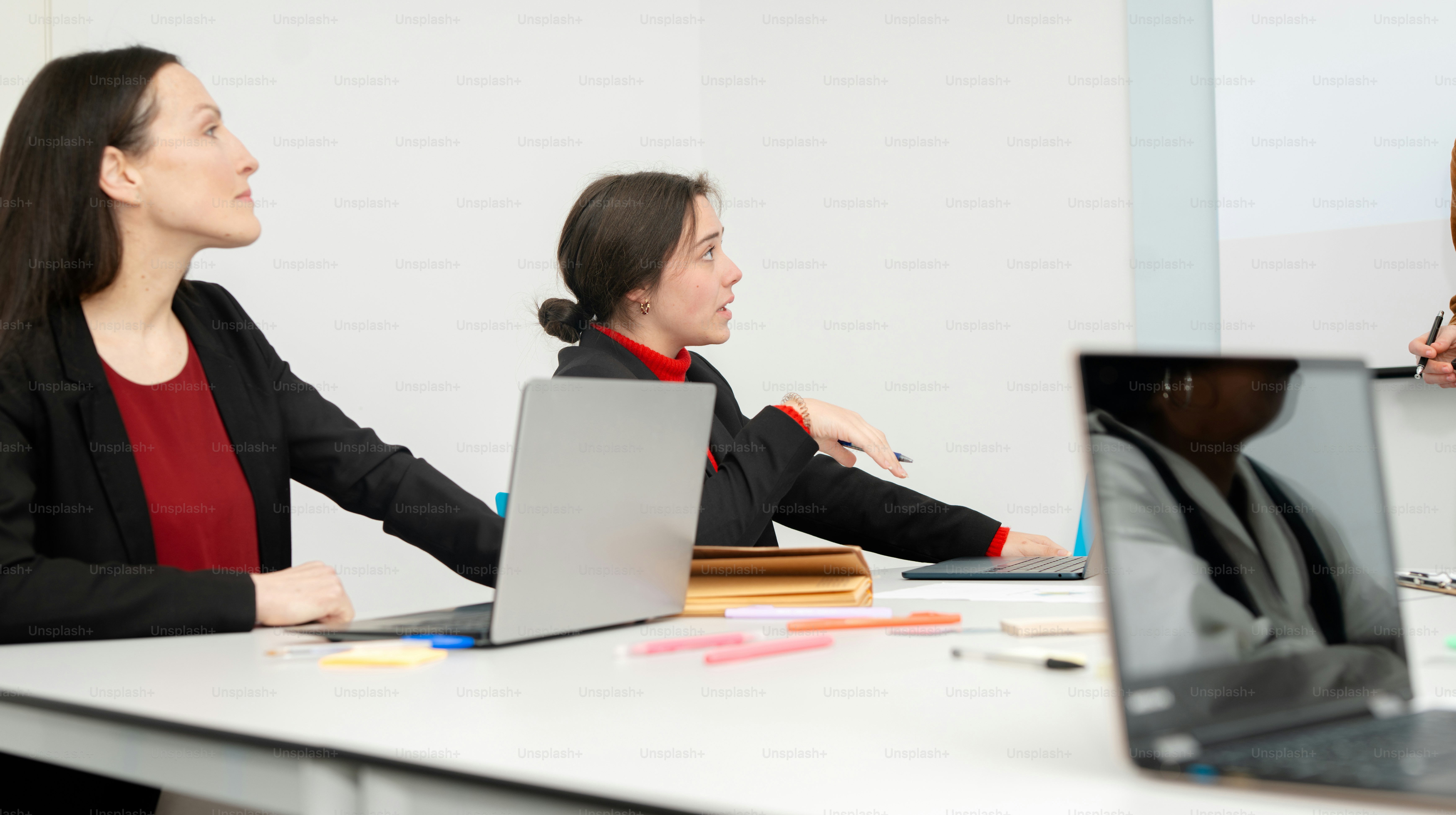 A group of people sitting at a table with laptops