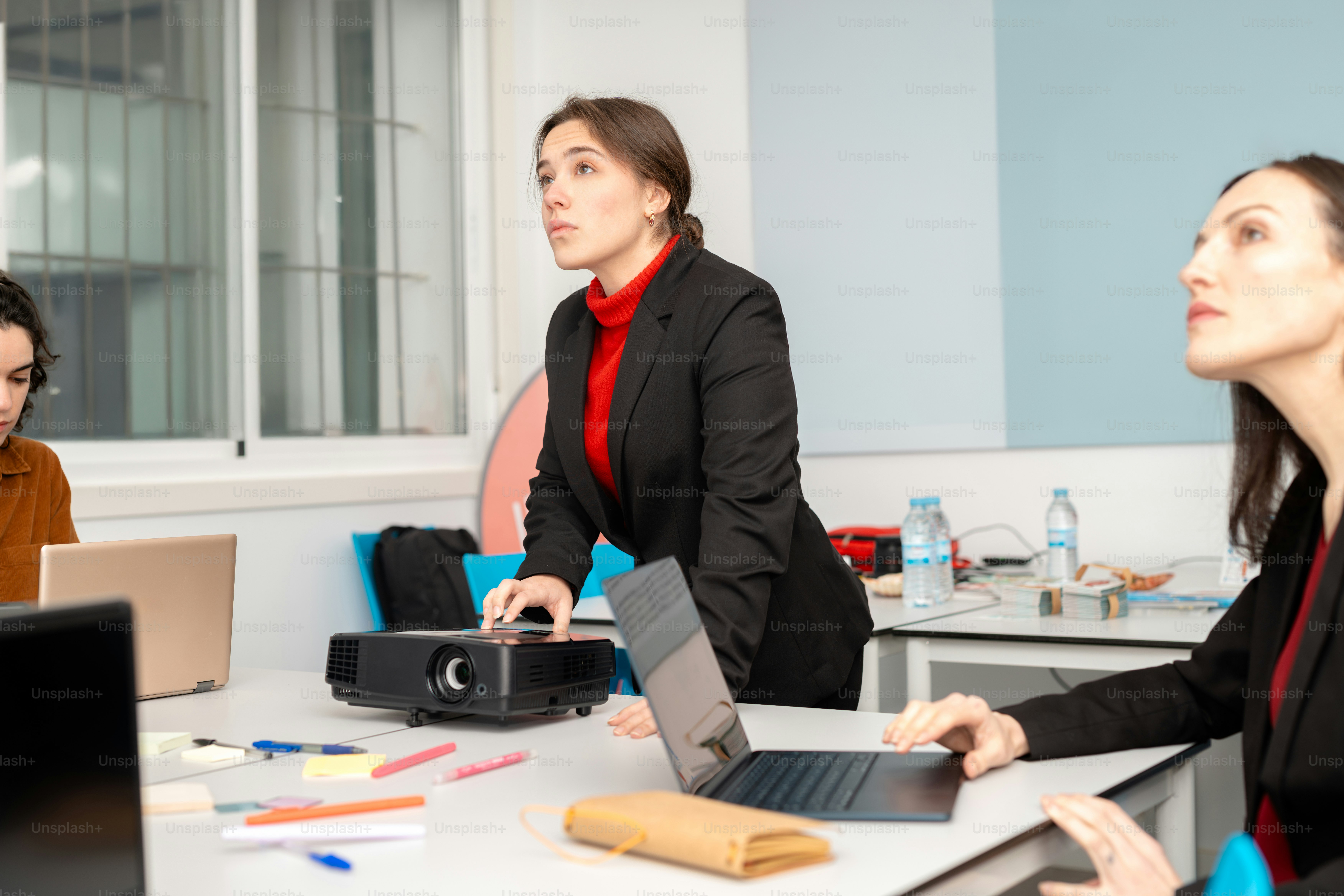 A group of people sitting around a table with laptops