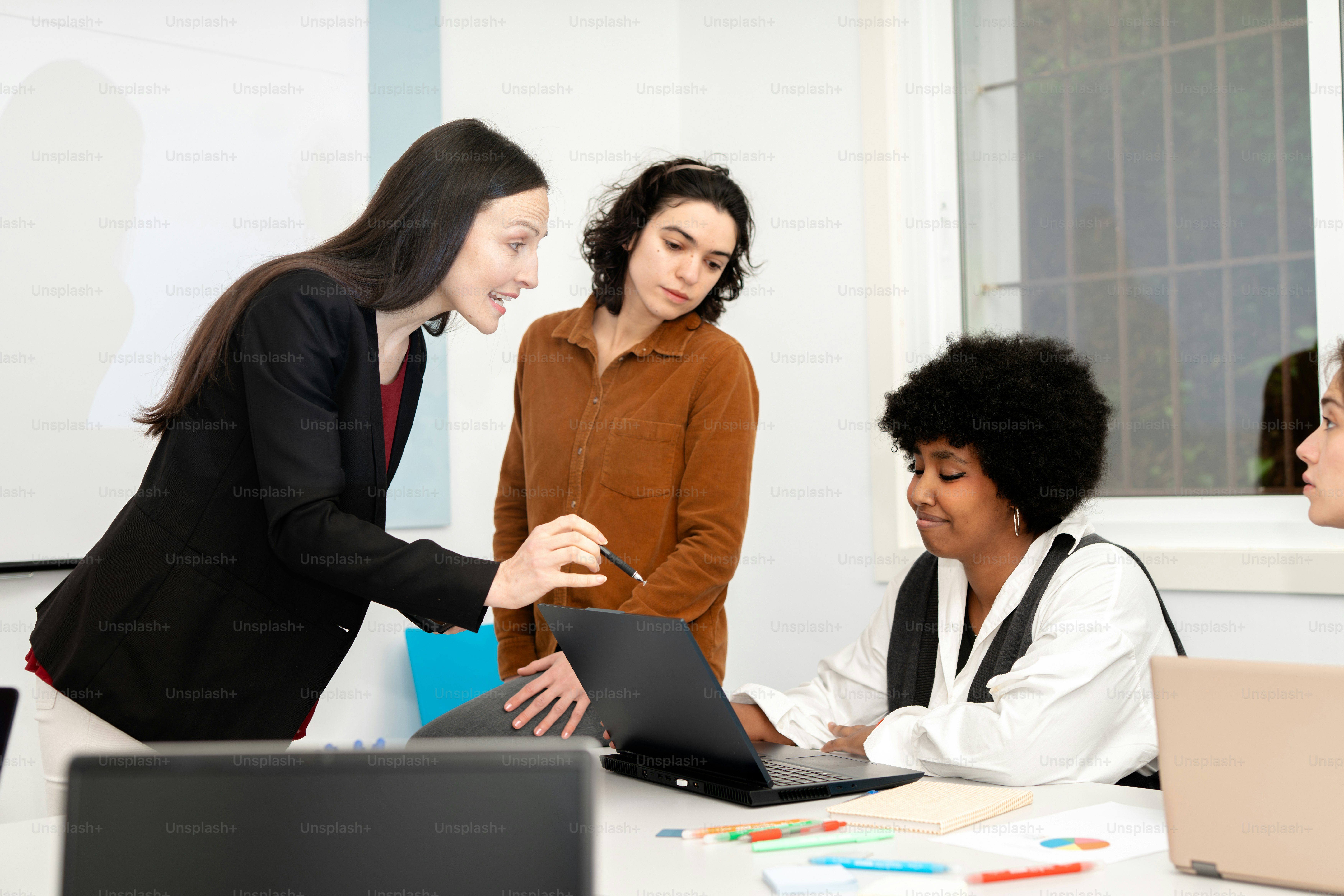 A group of people standing around a table with laptops