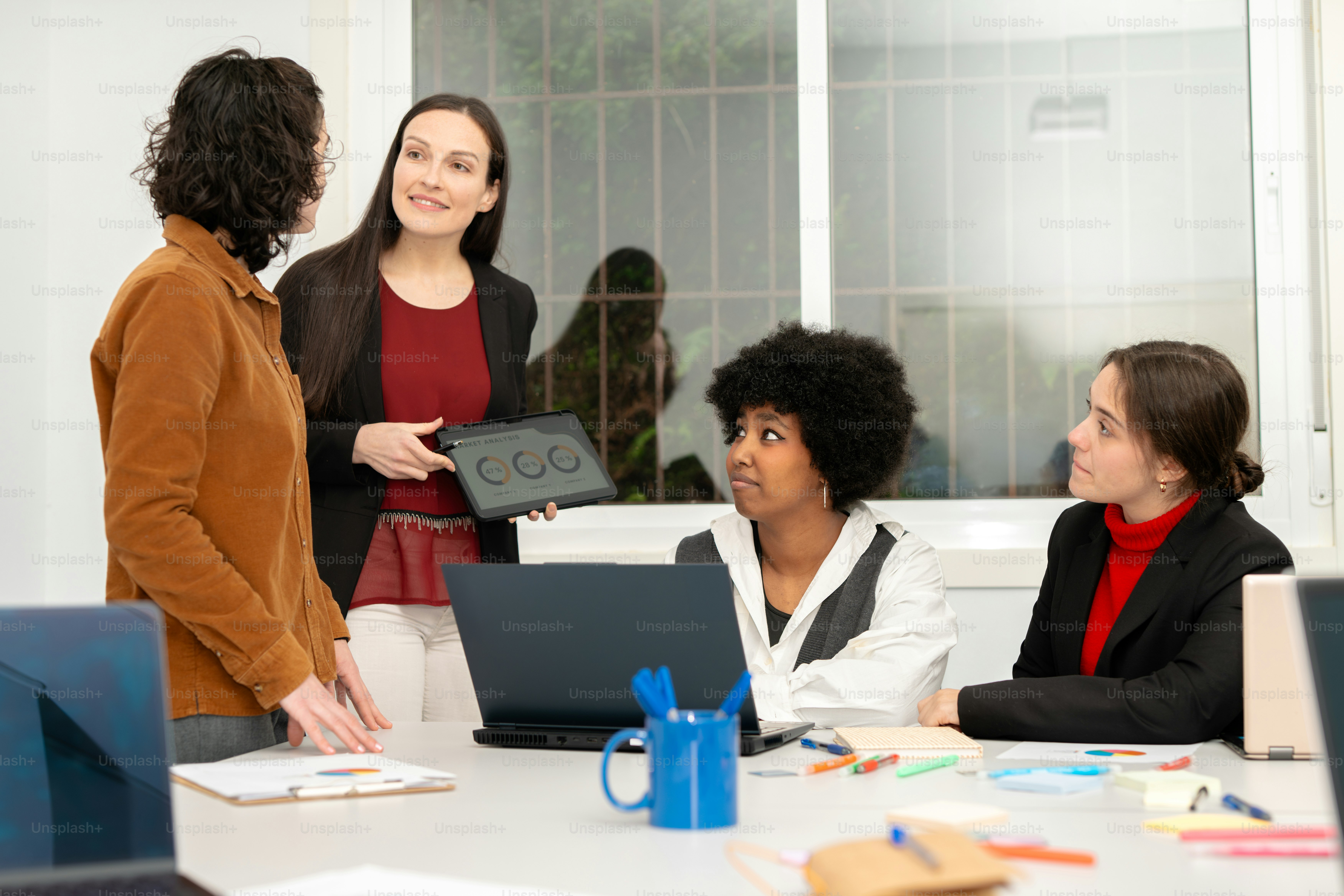 A group of people sitting around a table with laptops