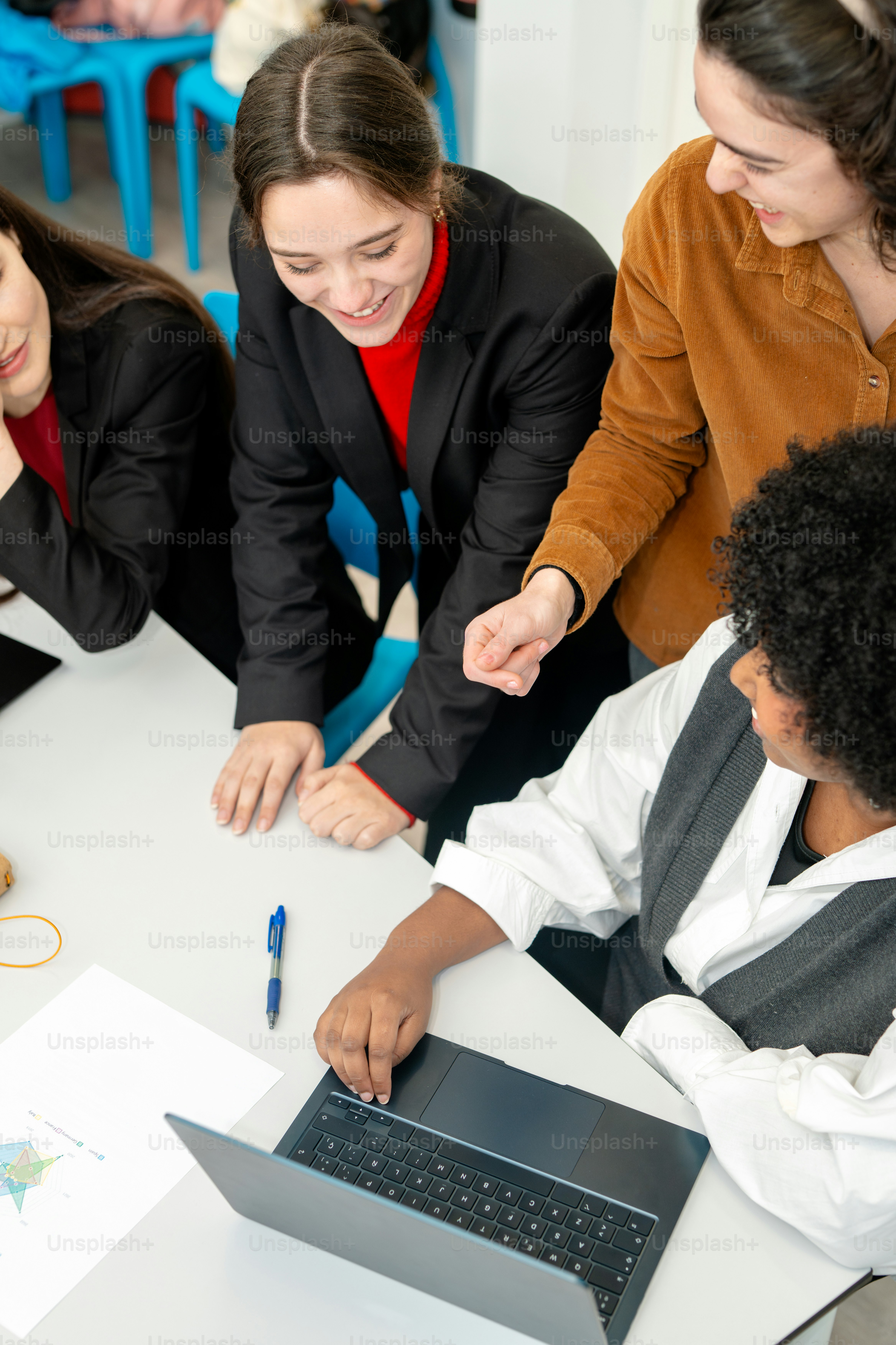 A group of people sitting around a table with a laptop photo – Office ...