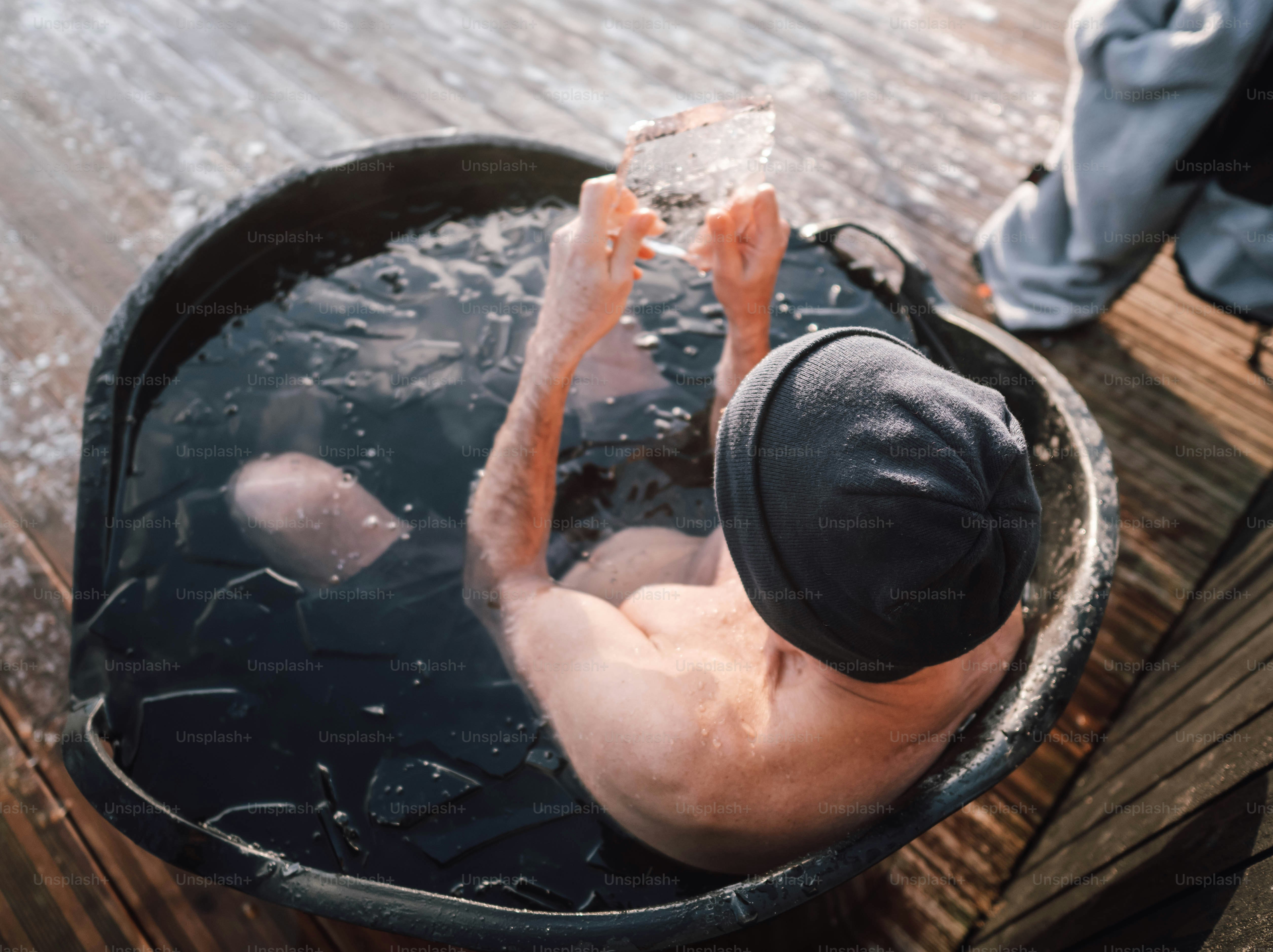 A man in a bucket of water with his feet in the water