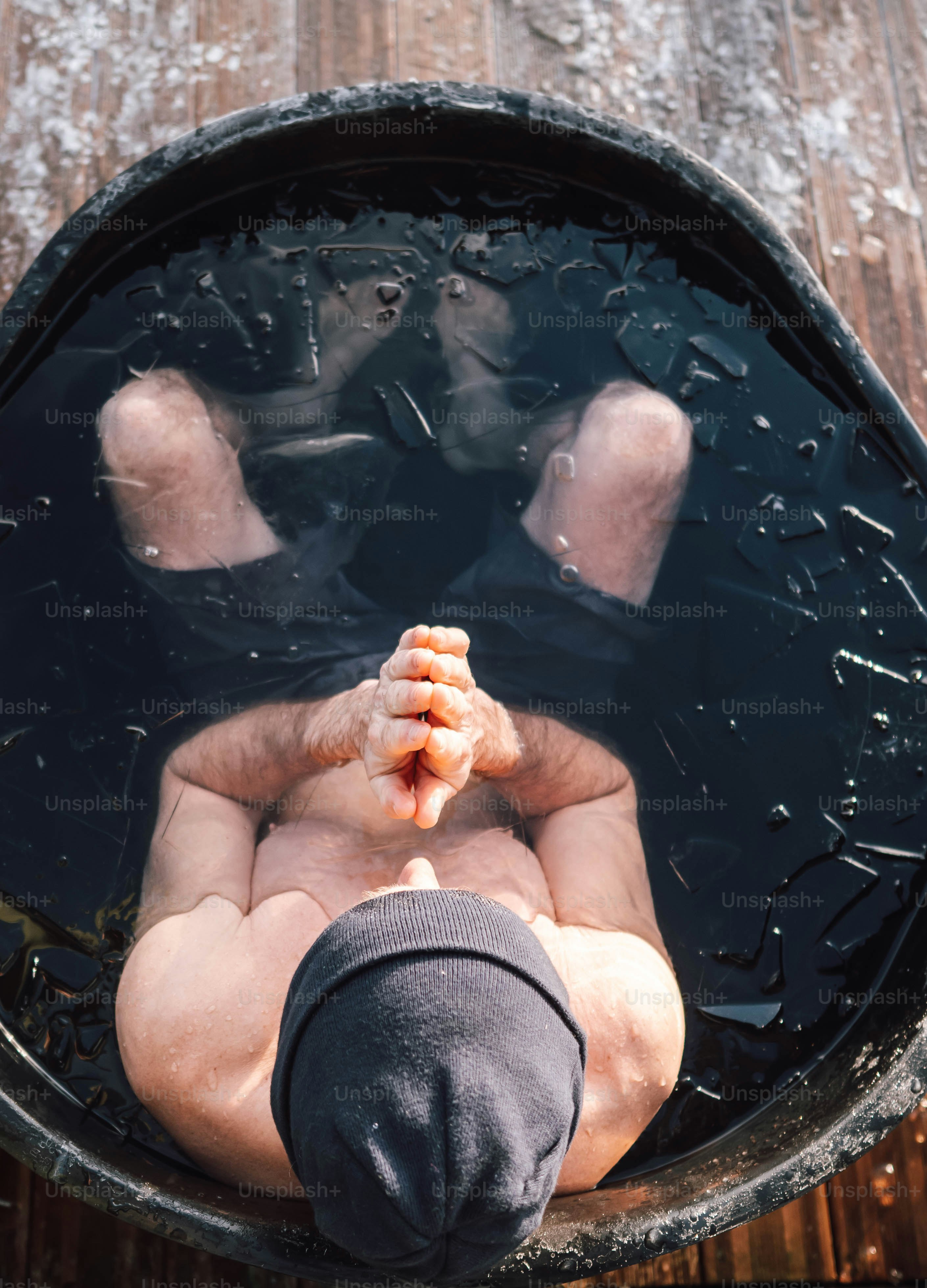 A man laying in a barrel with his feet in the water photo – Winter ...