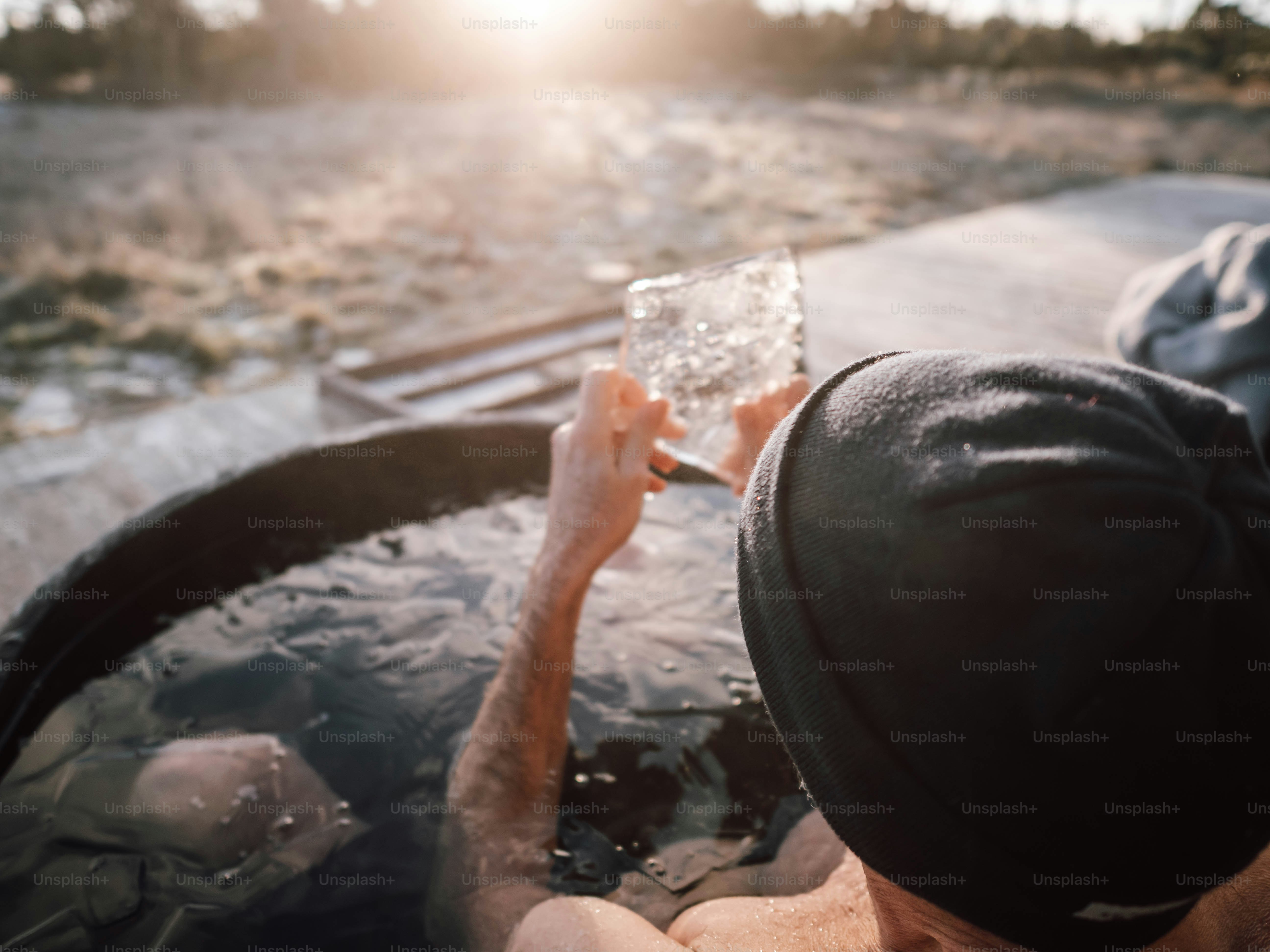 A man sitting in a hot tub holding a glass of water