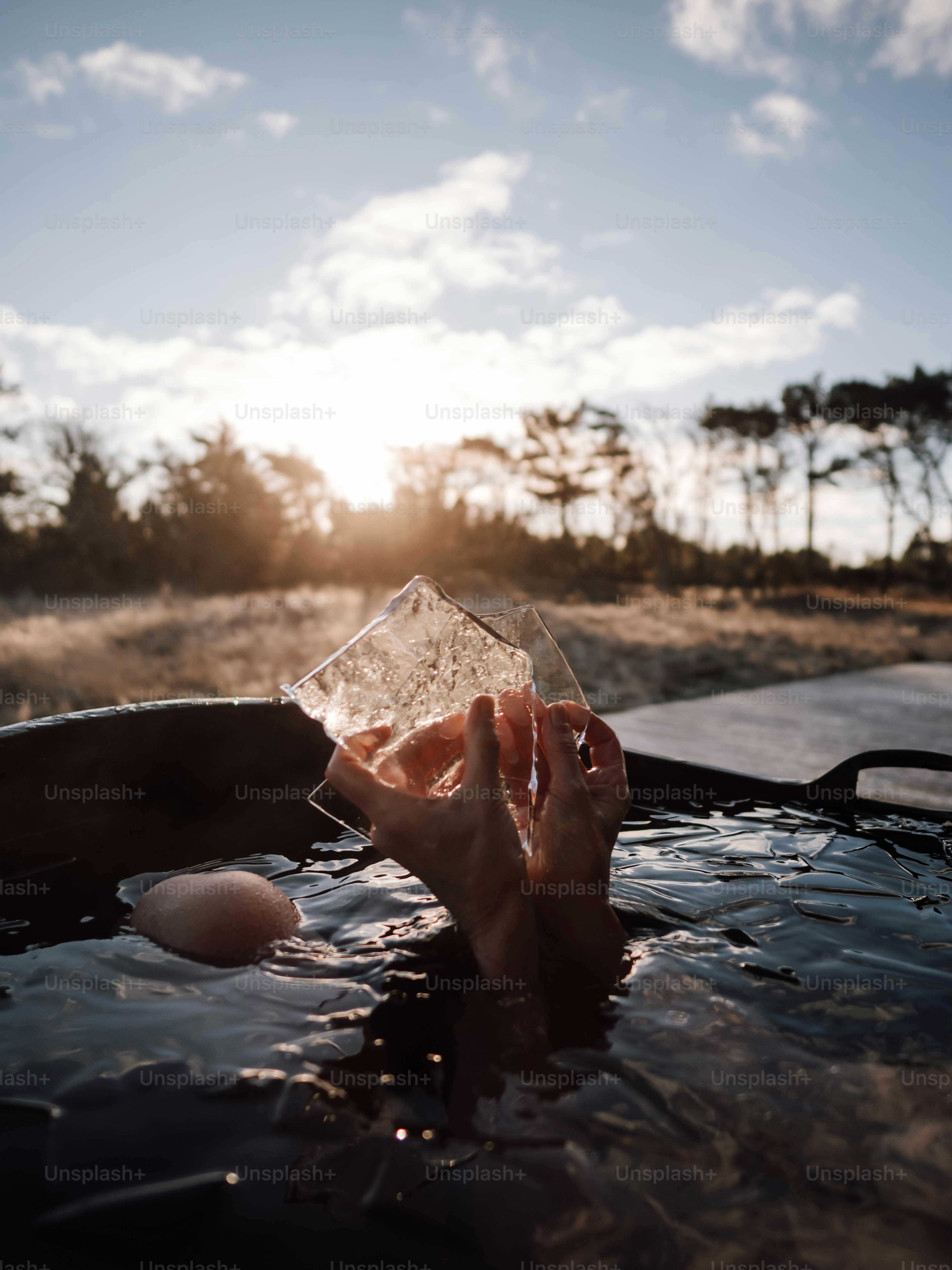 A person in a hot tub holding a glass of water