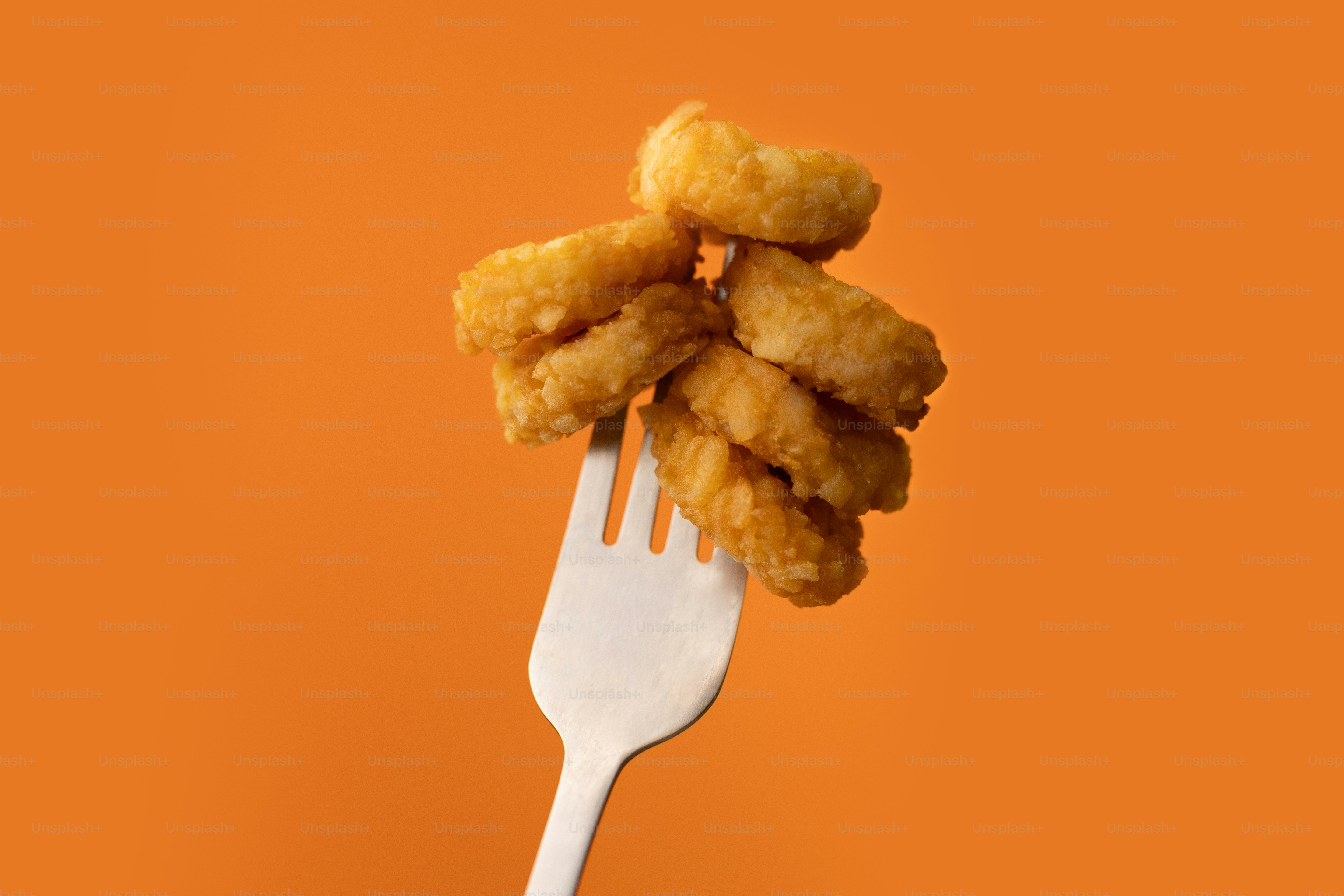 A fork full of fried food on an orange background