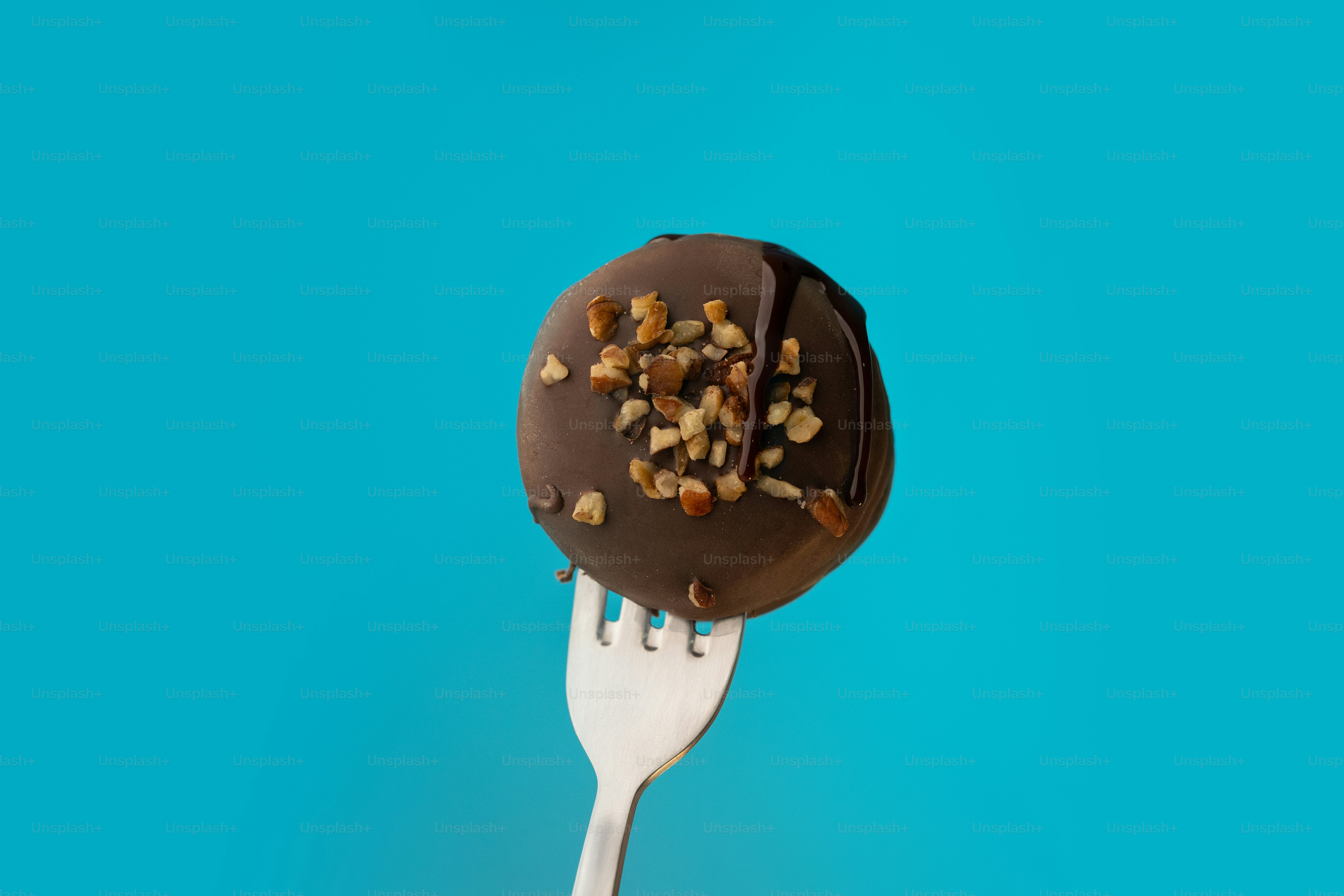 A fork with a chocolate covered donut on it