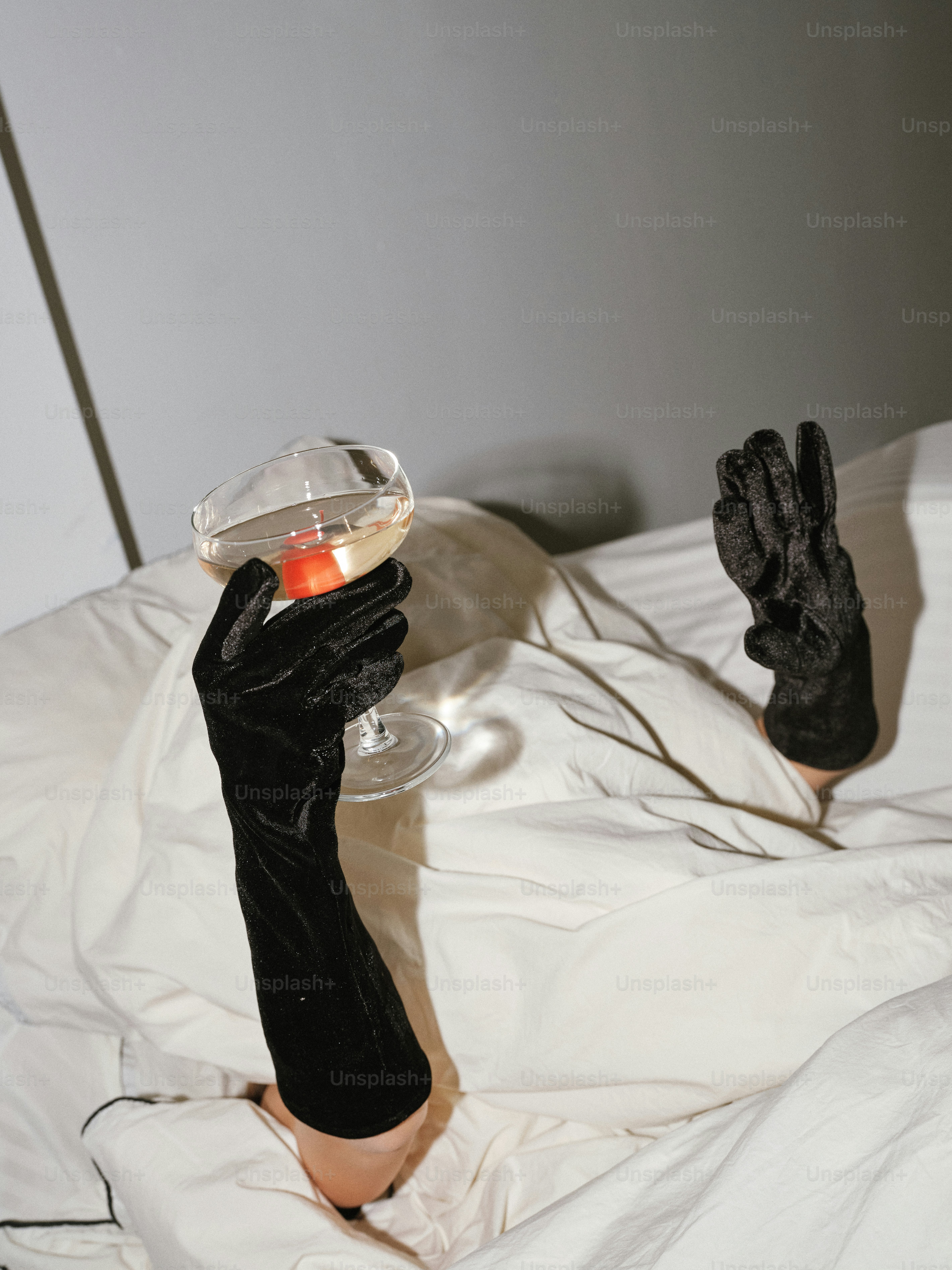 A person in black gloves holding a wine glass