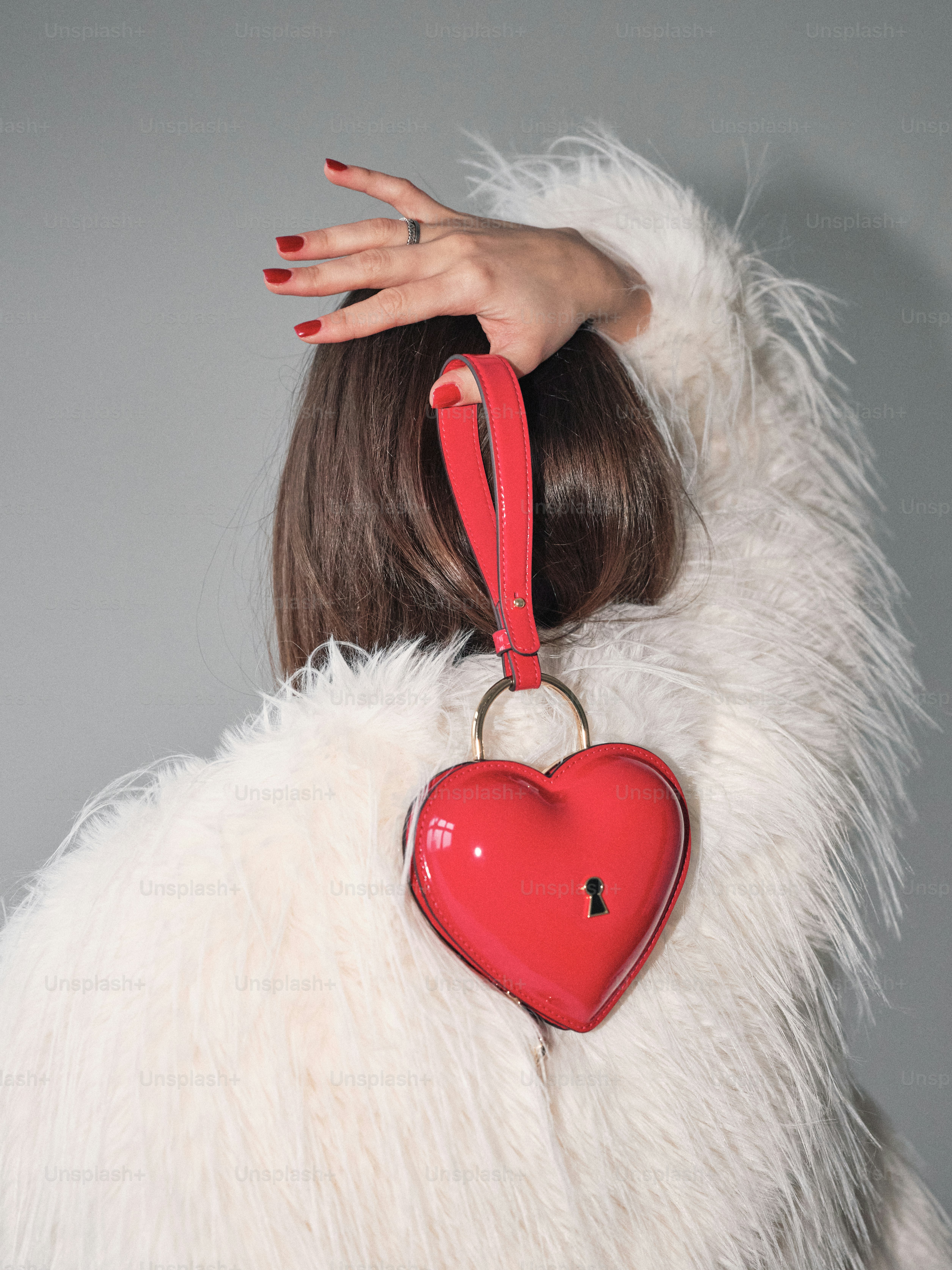 A woman in a fur coat holding a red heart shaped purse