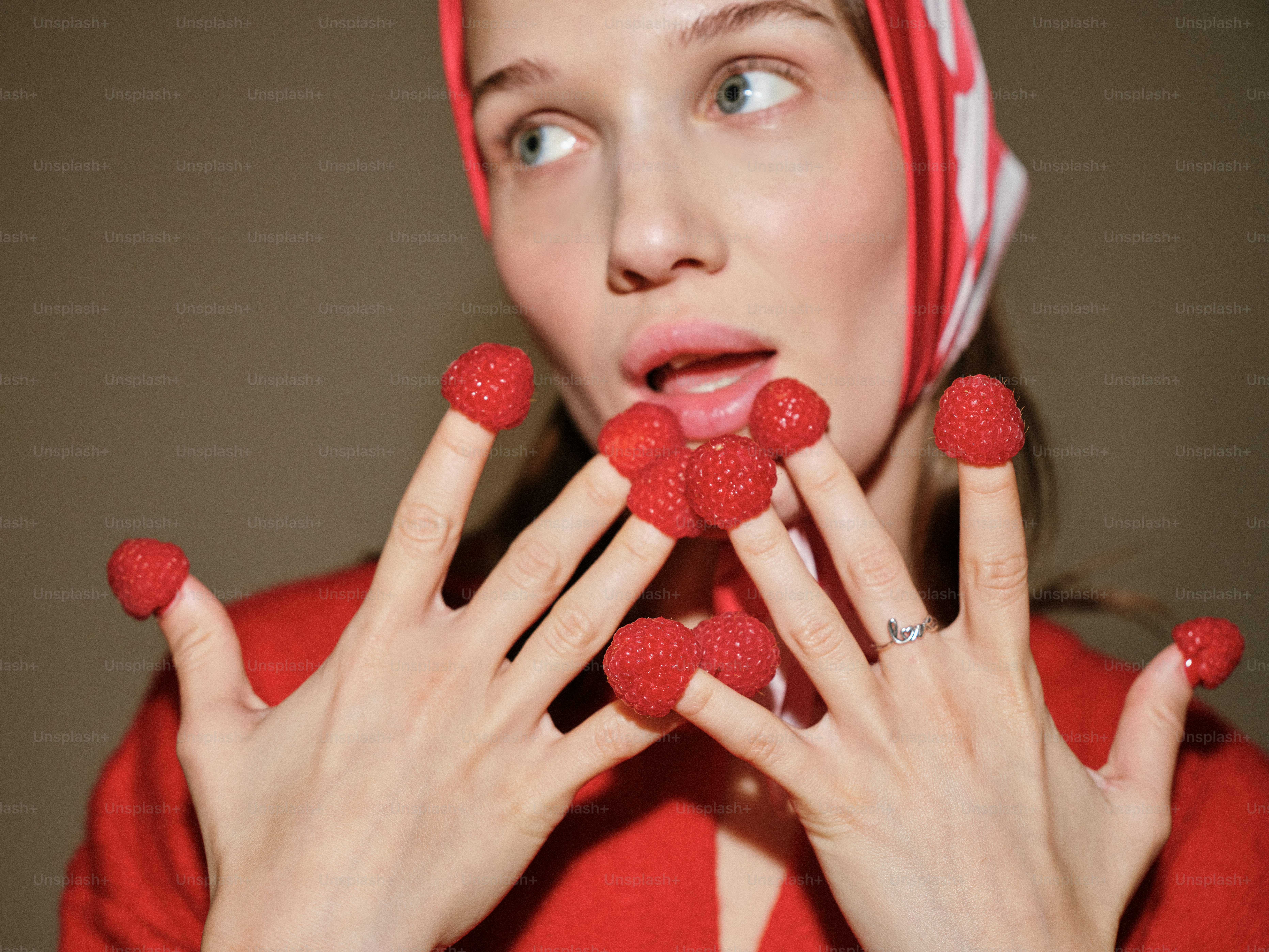 Una donna con una camicia rossa che tiene i lamponi davanti al viso