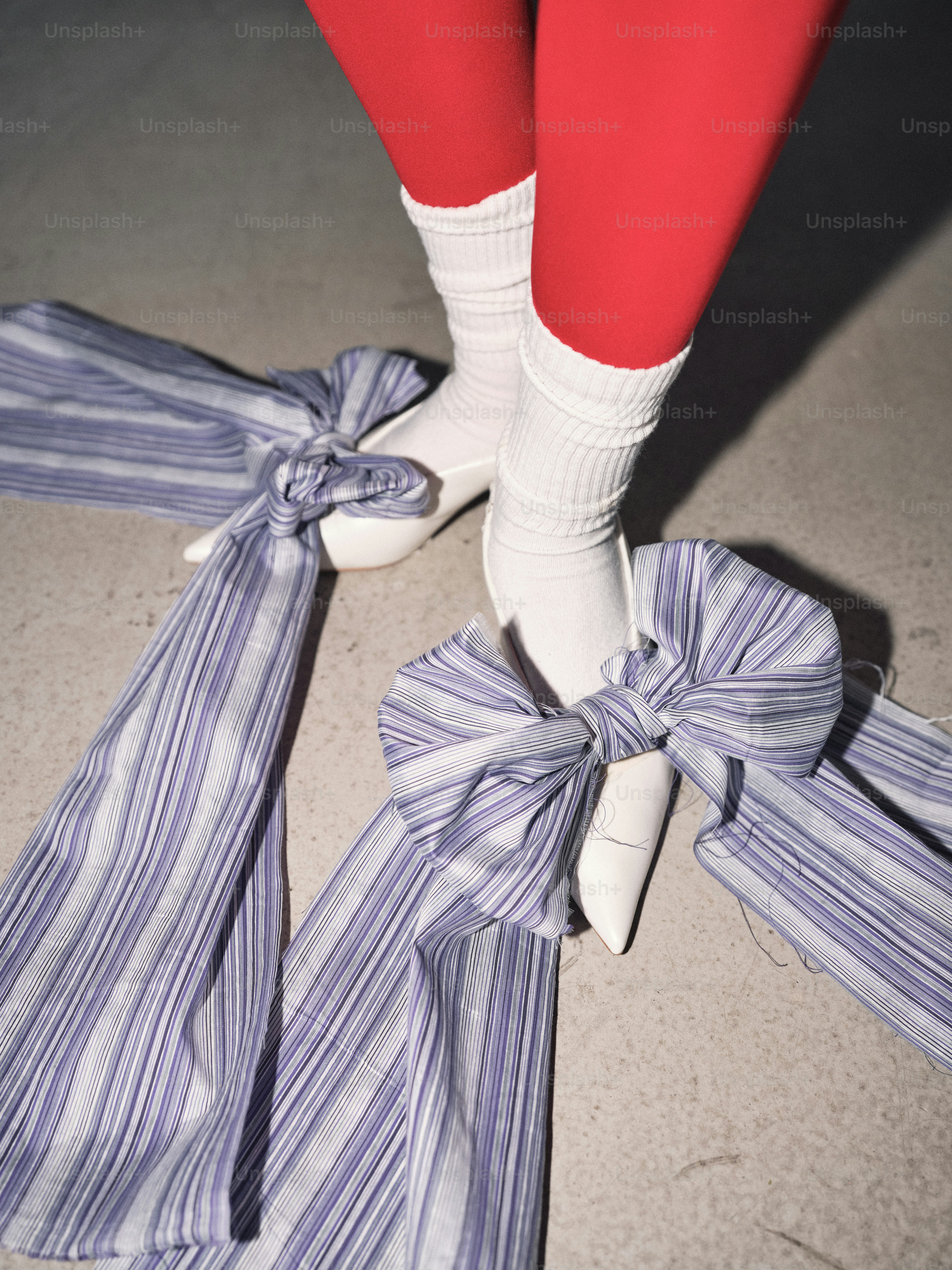 A woman's legs wearing white high heels and red tights