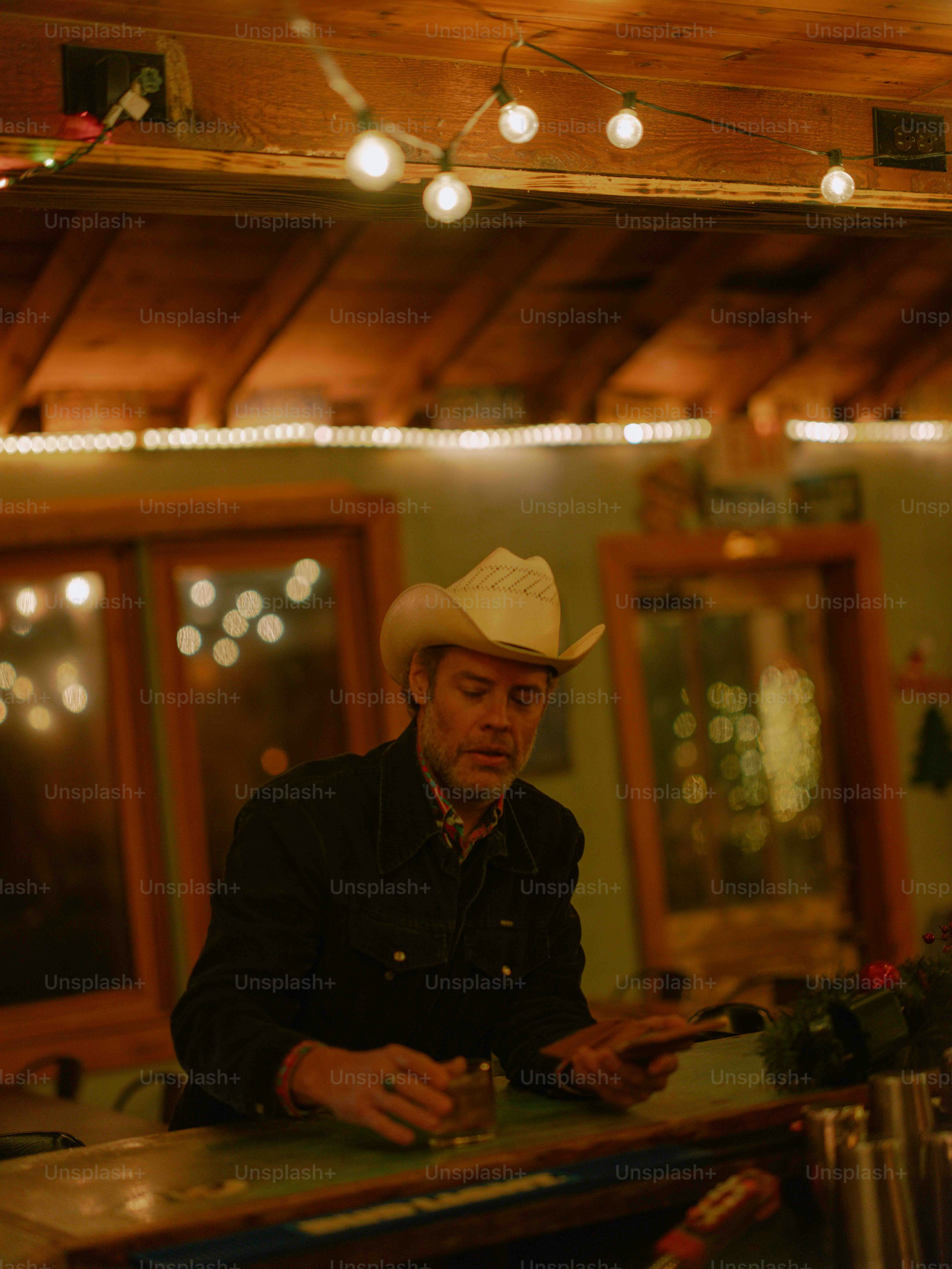 A man sitting at a bar wearing a cowboy hat