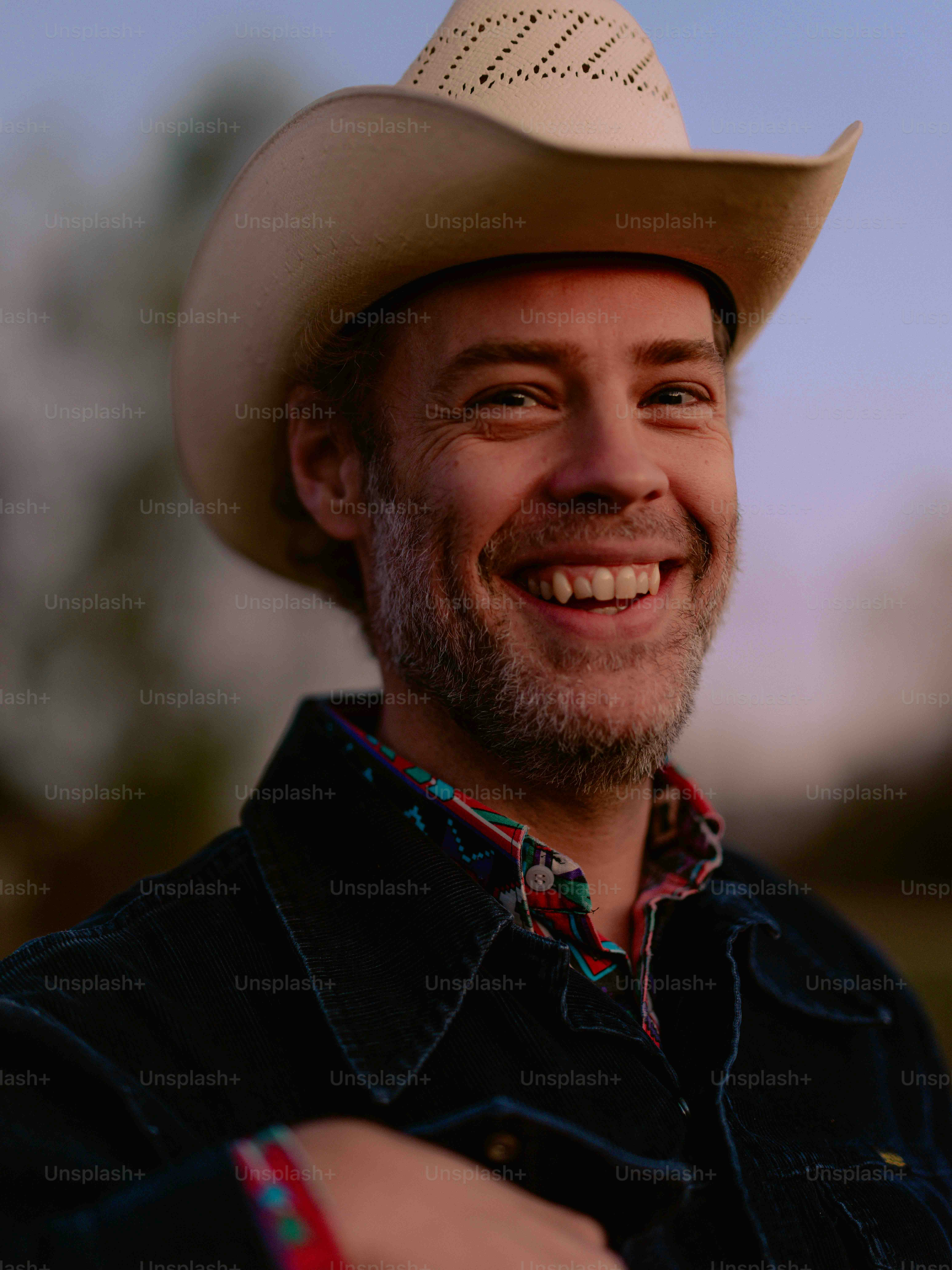A man wearing a cowboy hat smiles at the camera