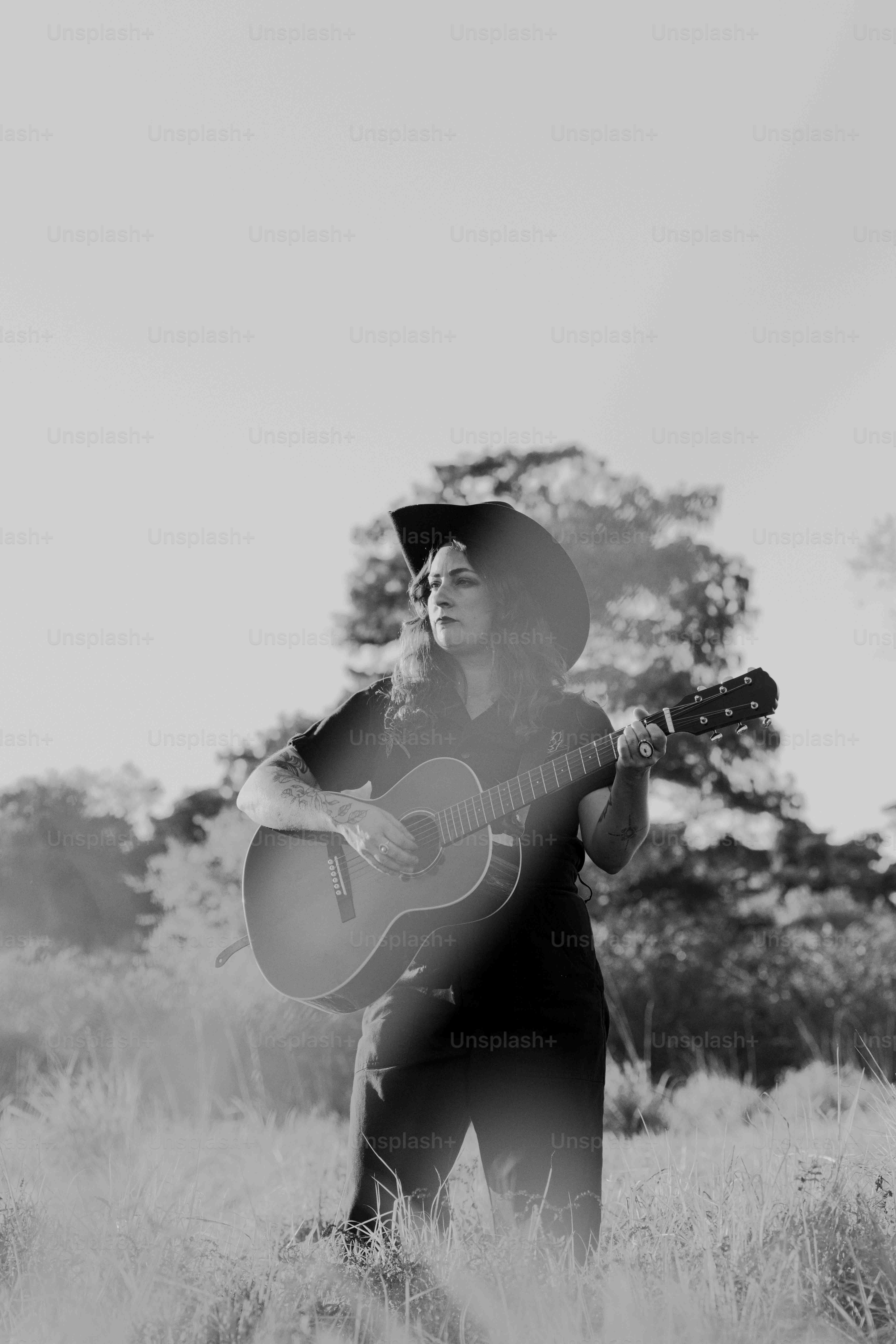 Un hombre de pie en un campo sosteniendo una guitarra