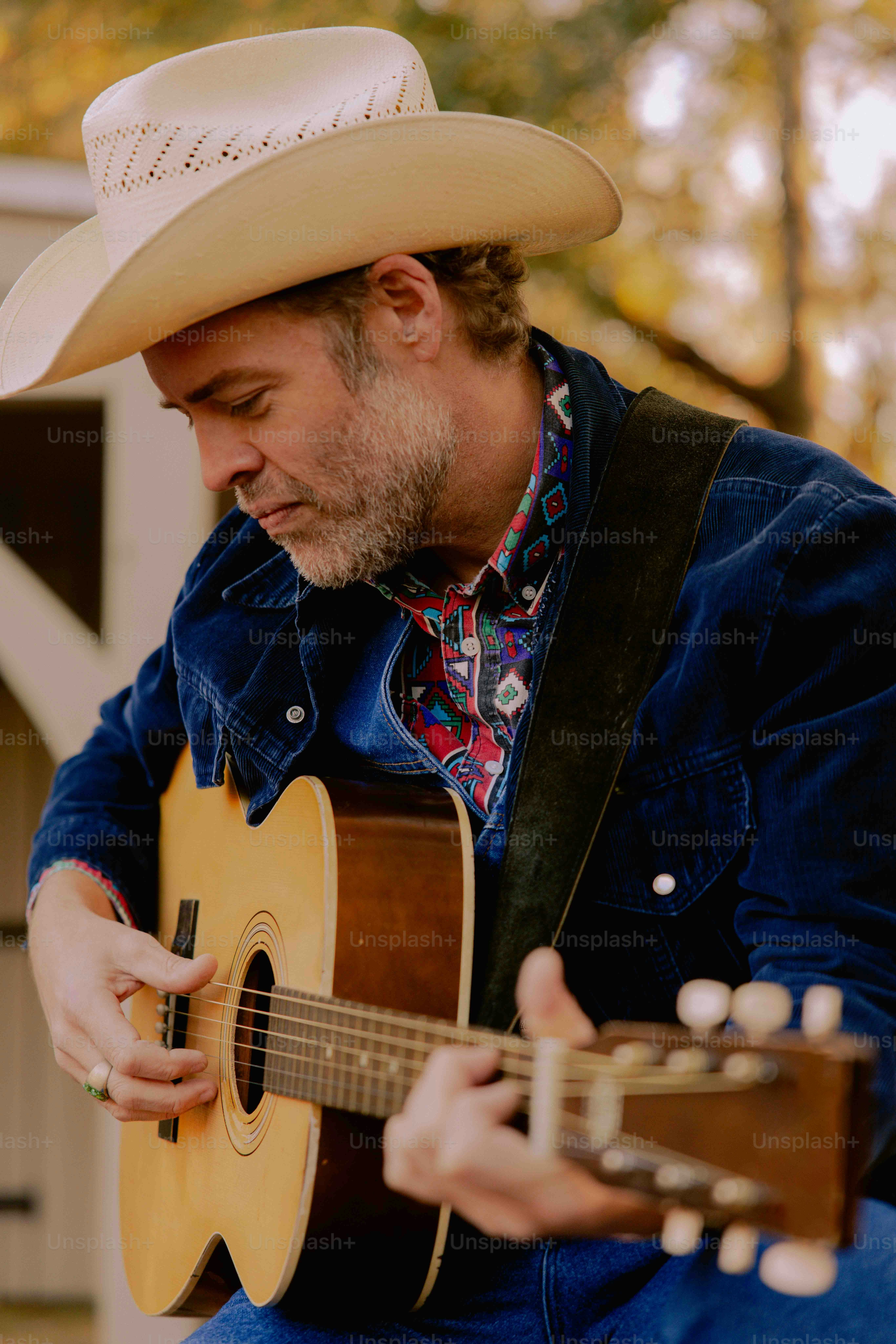 A man with a cowboy hat playing a guitar