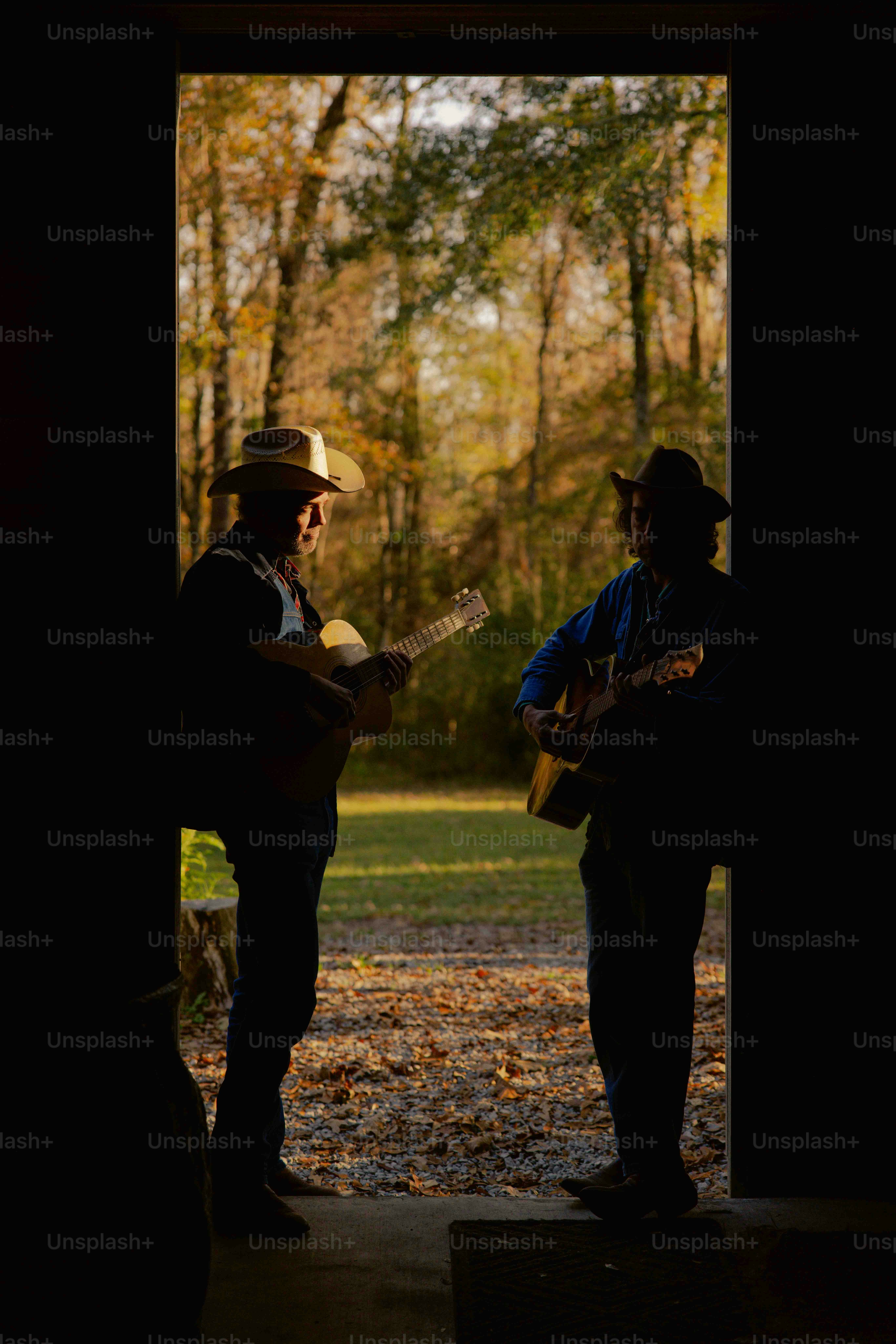 Two men are playing guitars in a doorway