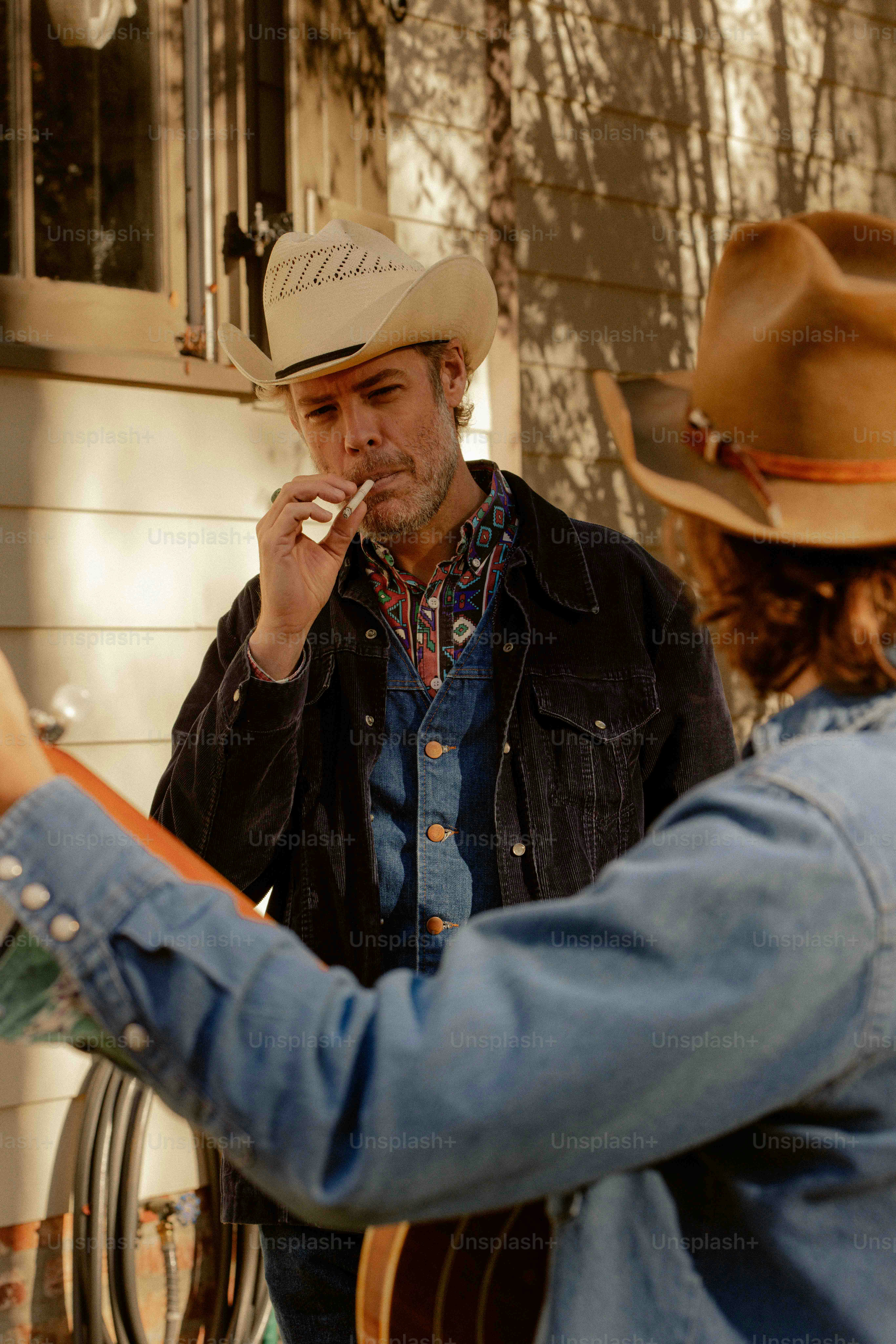 A man in a cowboy hat smoking a cigarette