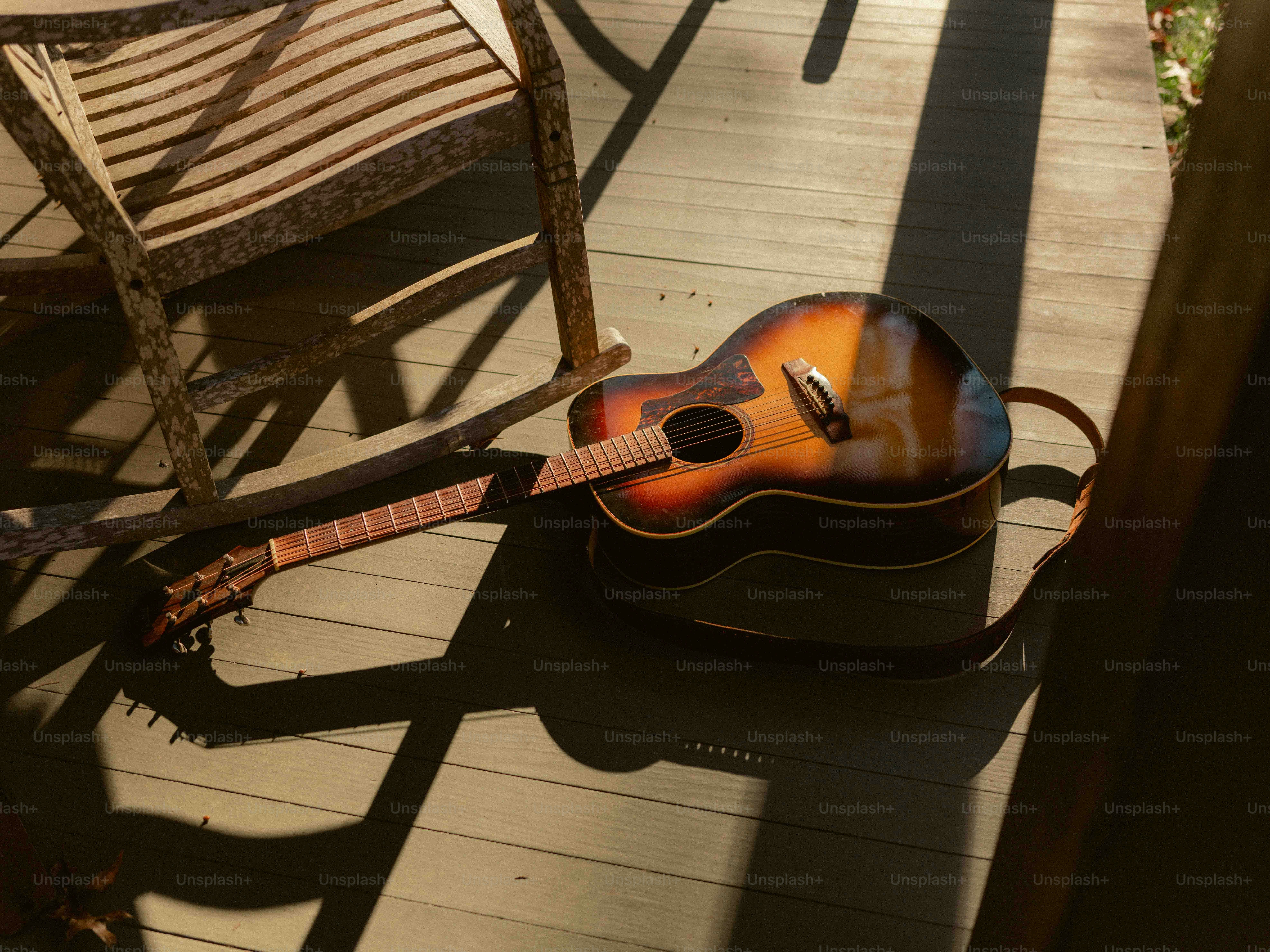 A guitar sitting on a porch next to a chair