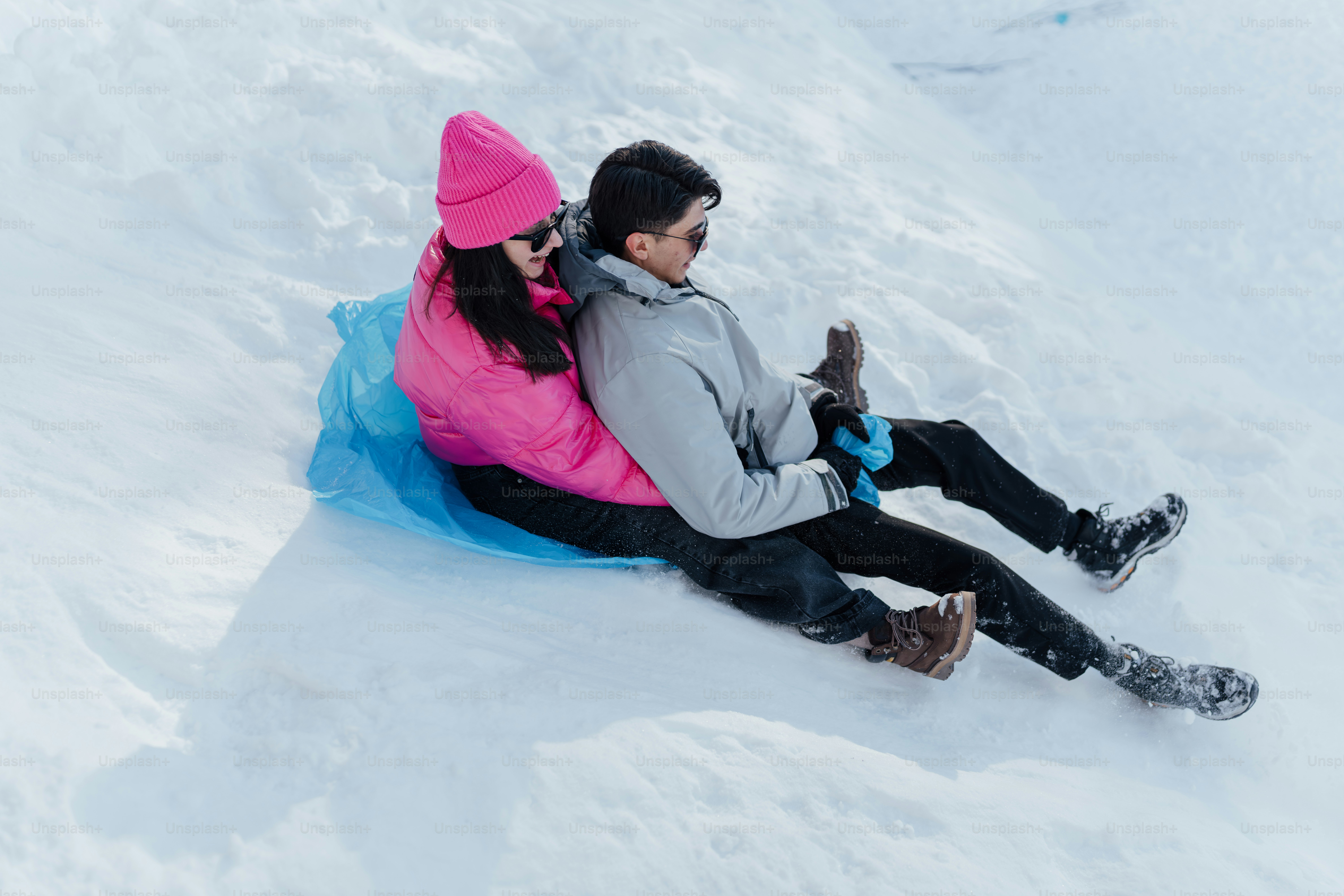 Un hombre y una mujer bajan en trineo por una colina