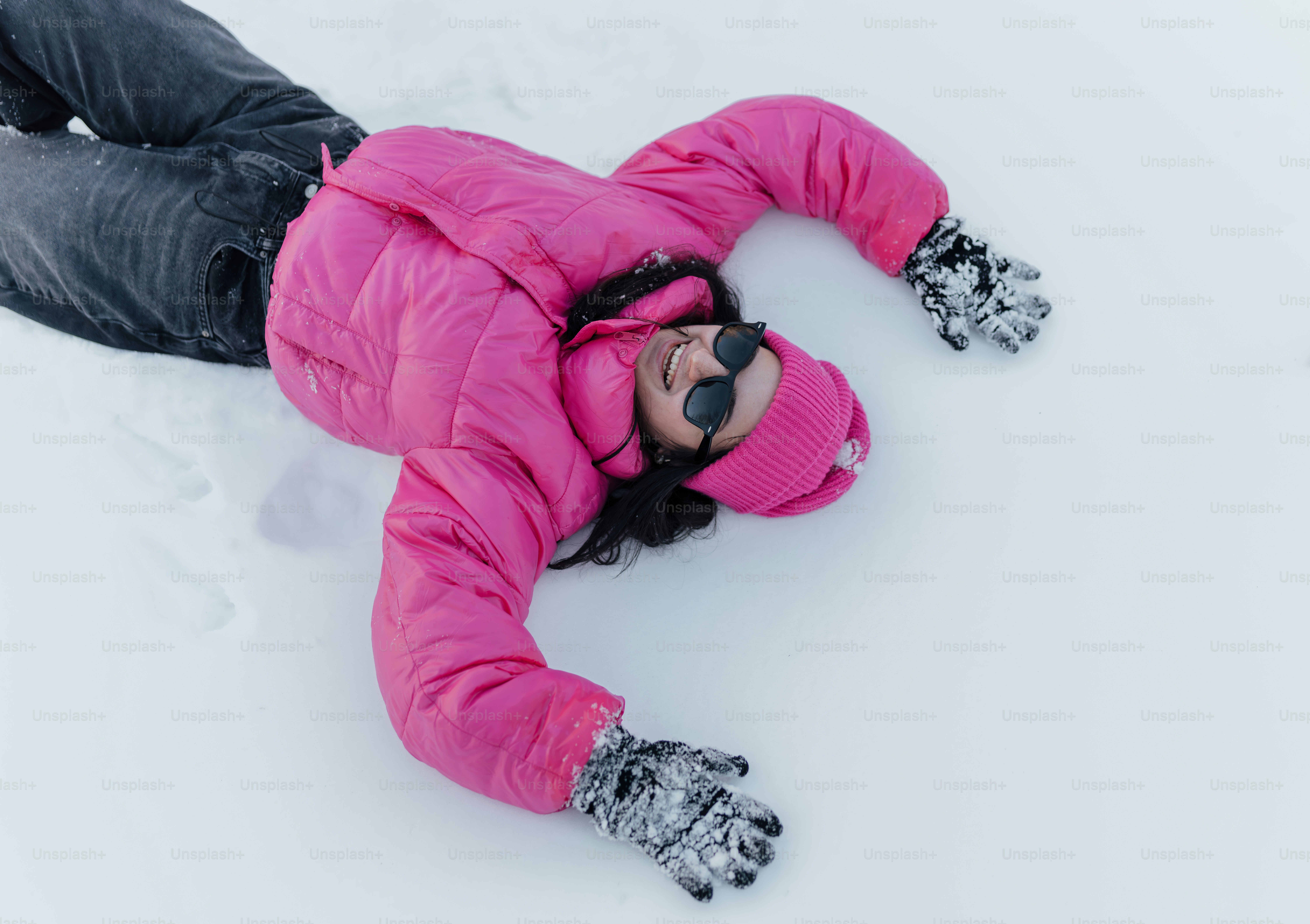 ピンクのジャケットを着た女性が雪の中に横たわる