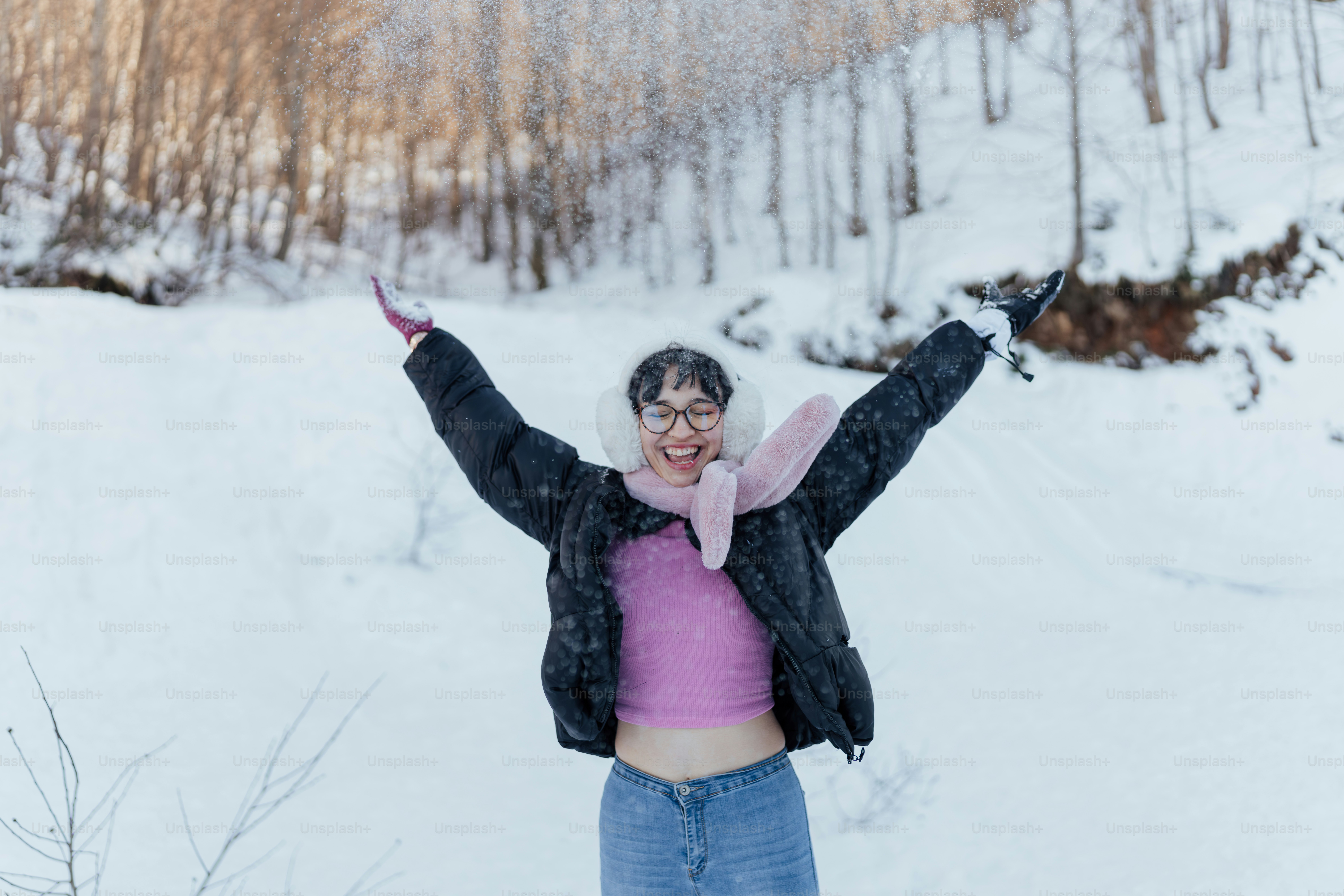 A woman standing in the snow with her arms in the air
