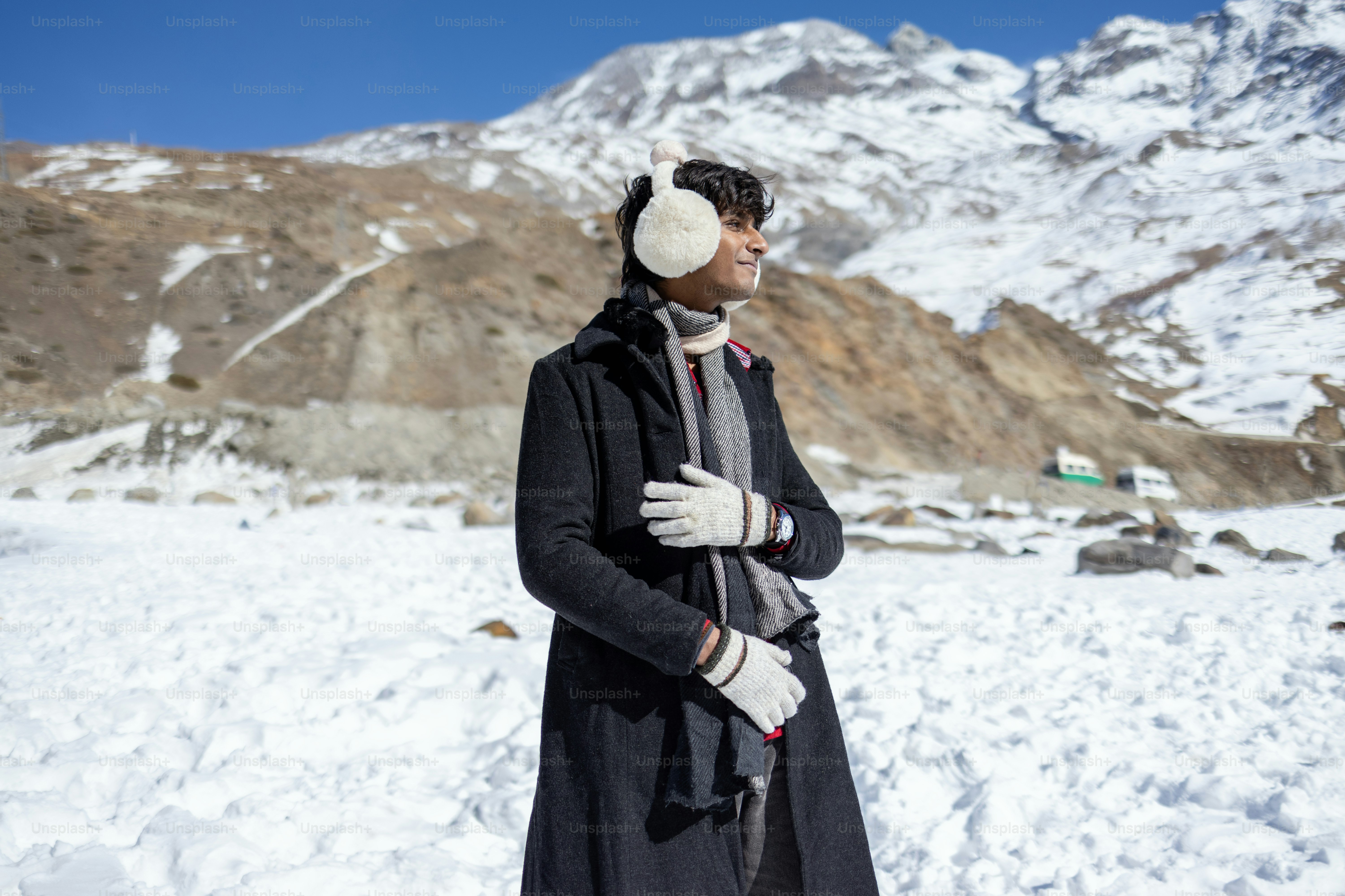 Un uomo in piedi nella neve che indossa un cappotto e un cappello