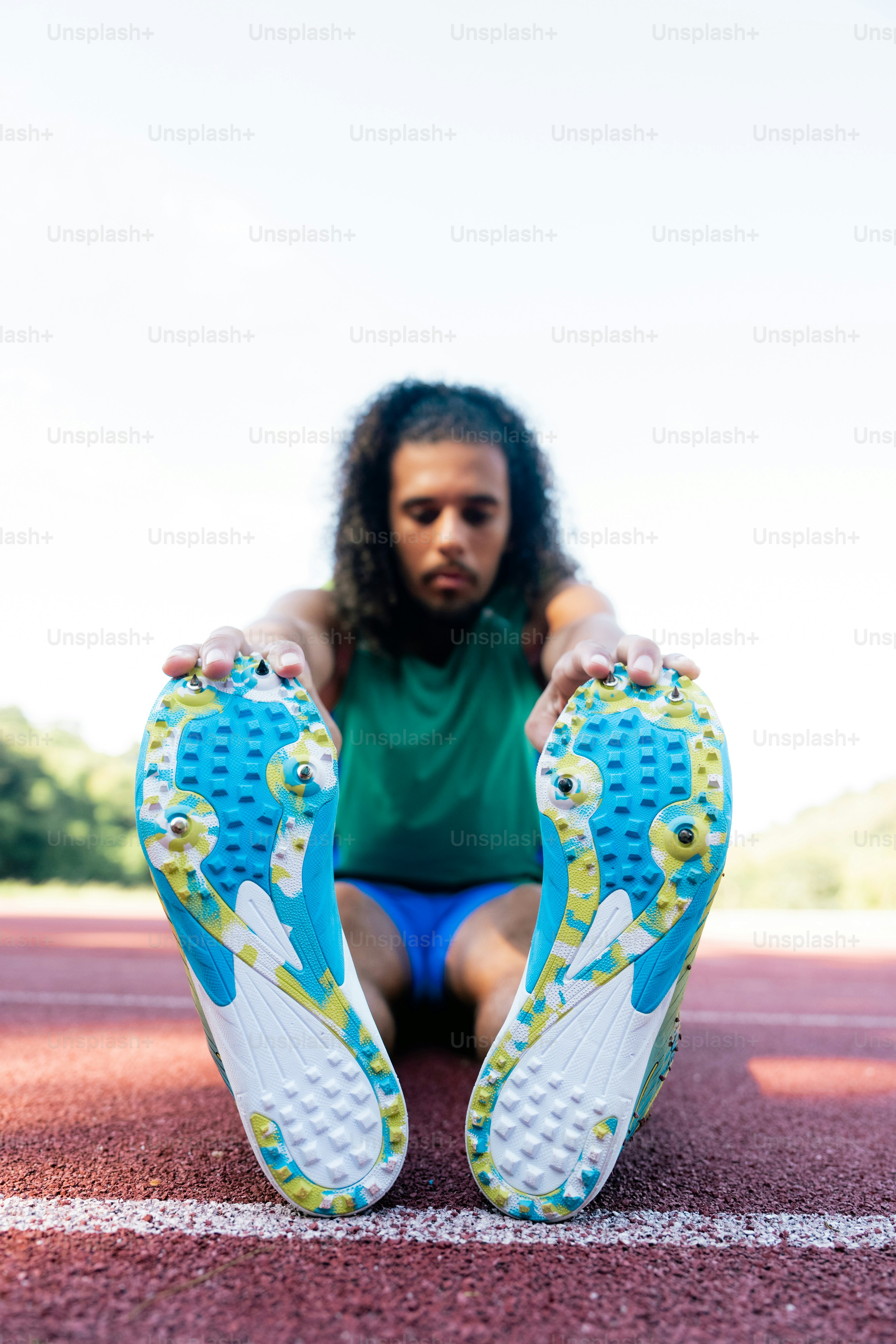 A man sitting on a running track with his feet on the ground