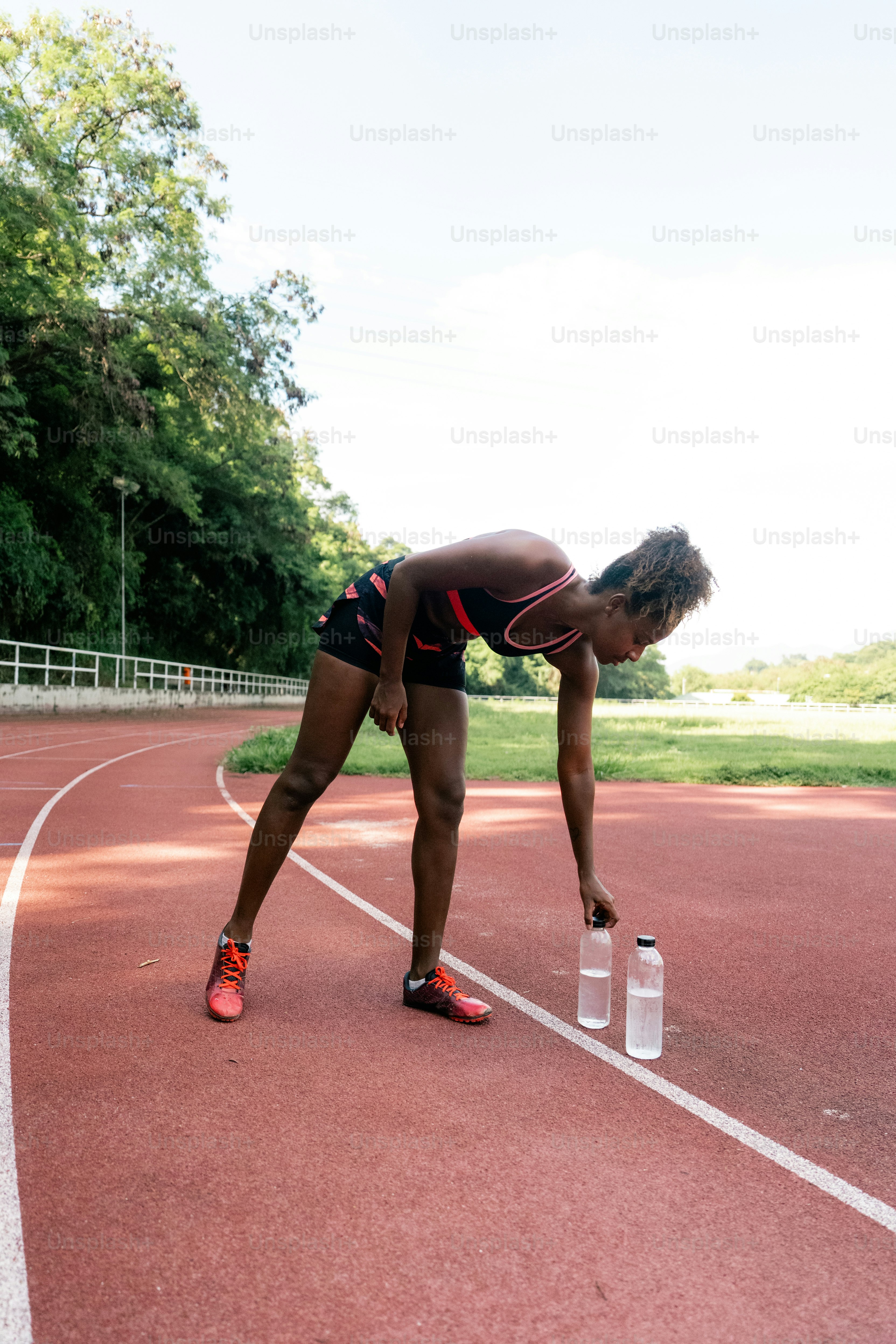 A woman leaning over a water bottle on a track