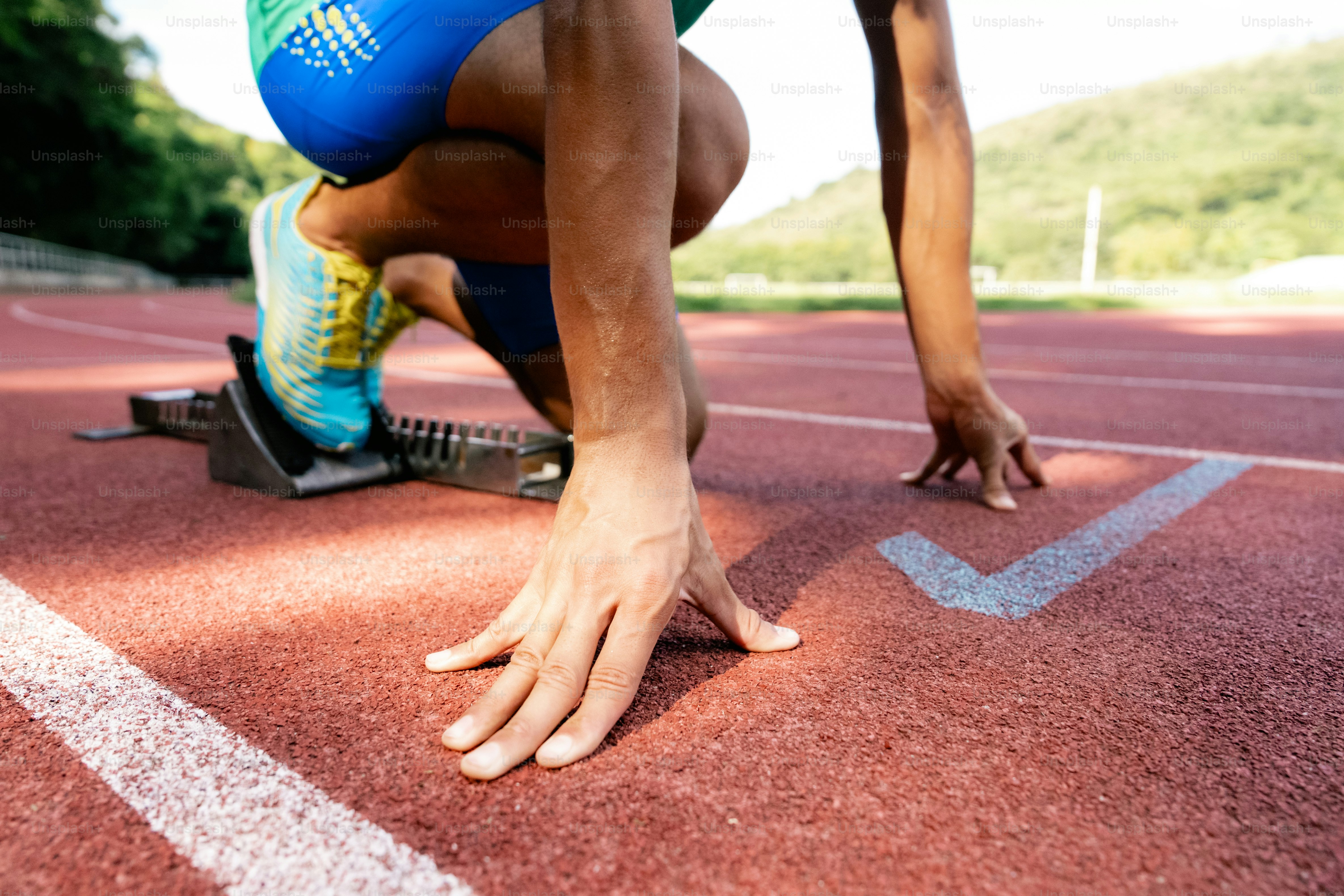 Ein Mann kniet auf einer Laufbahn