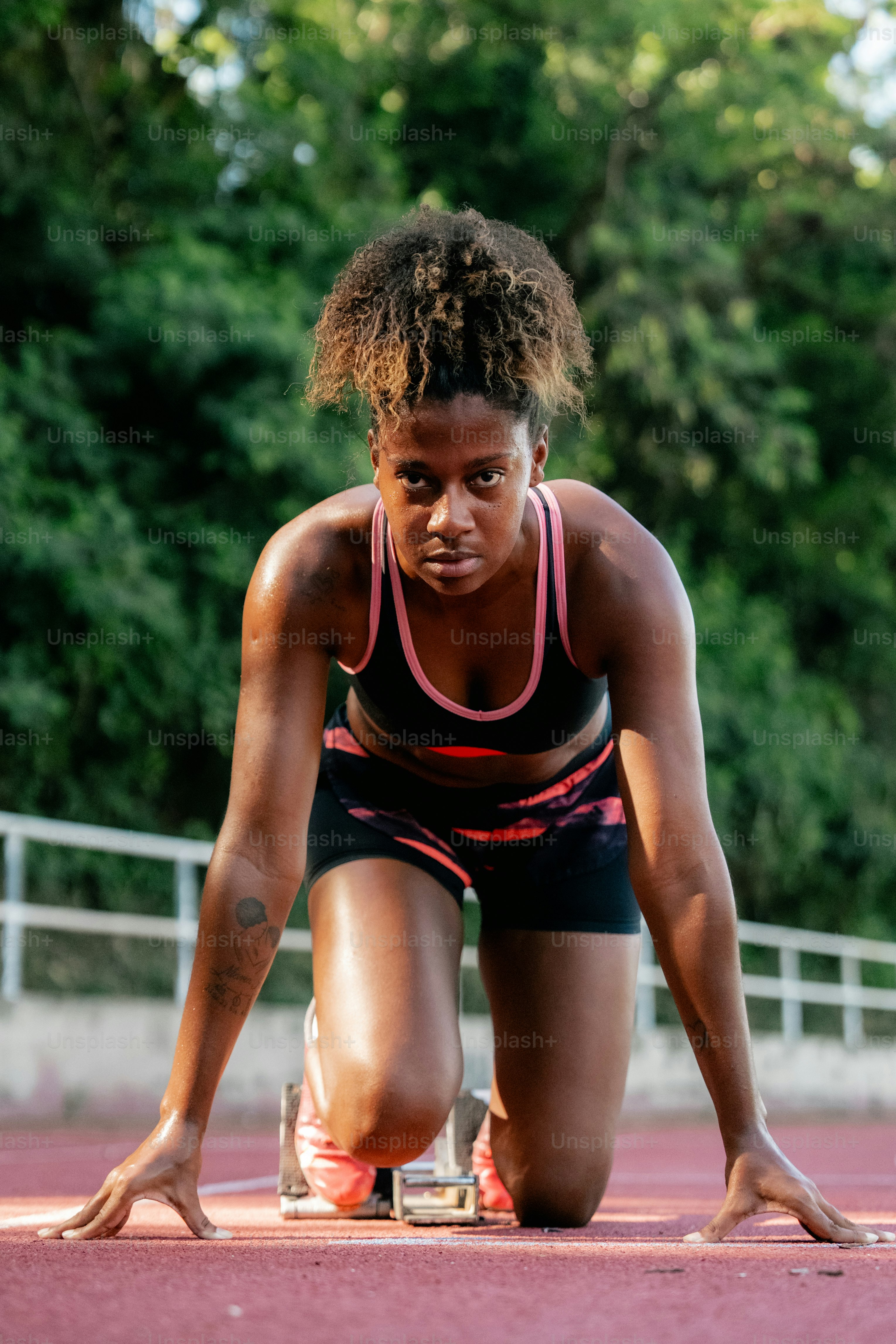 A woman kneeling down on a running track