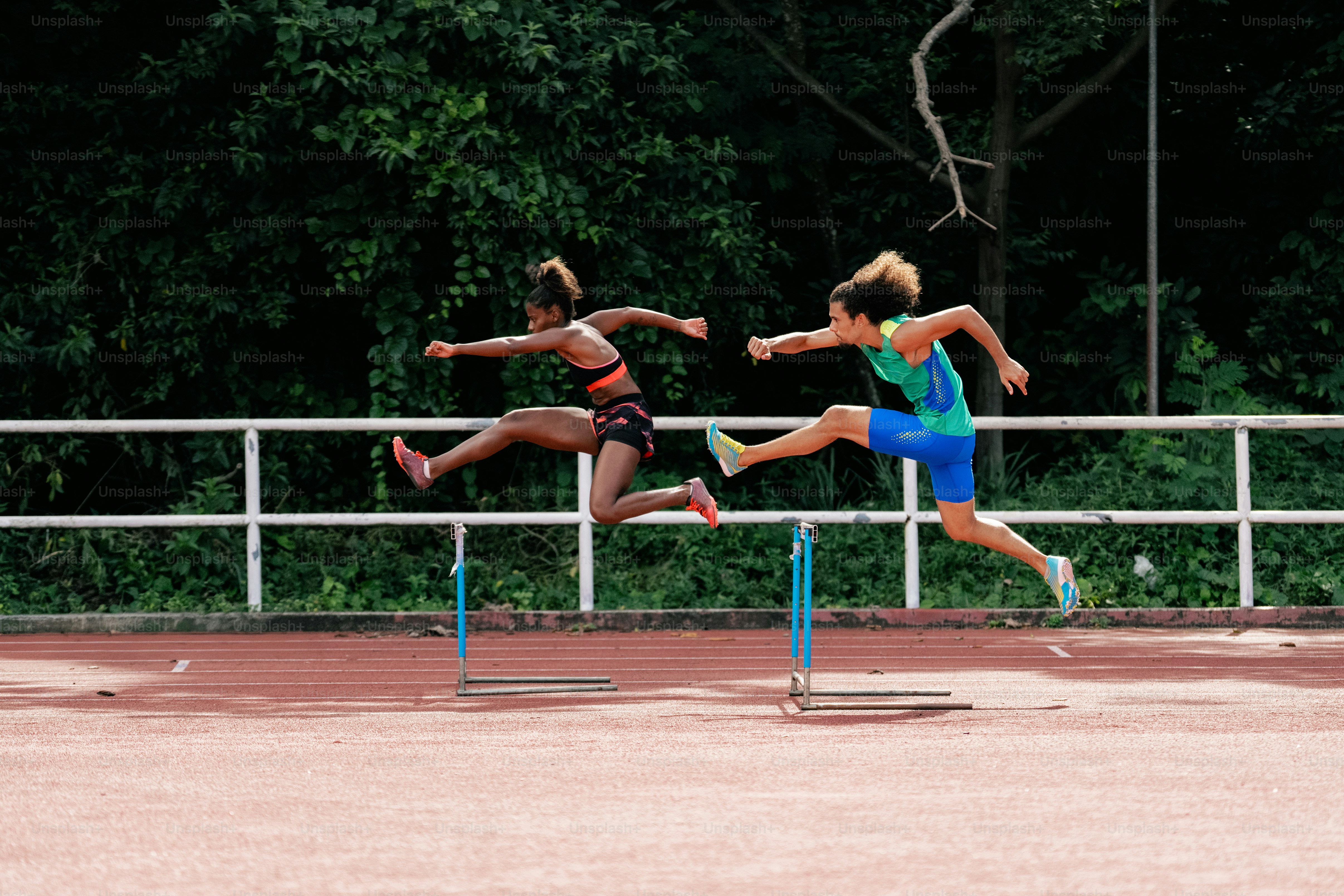 A couple of people that are jumping over a hurdle