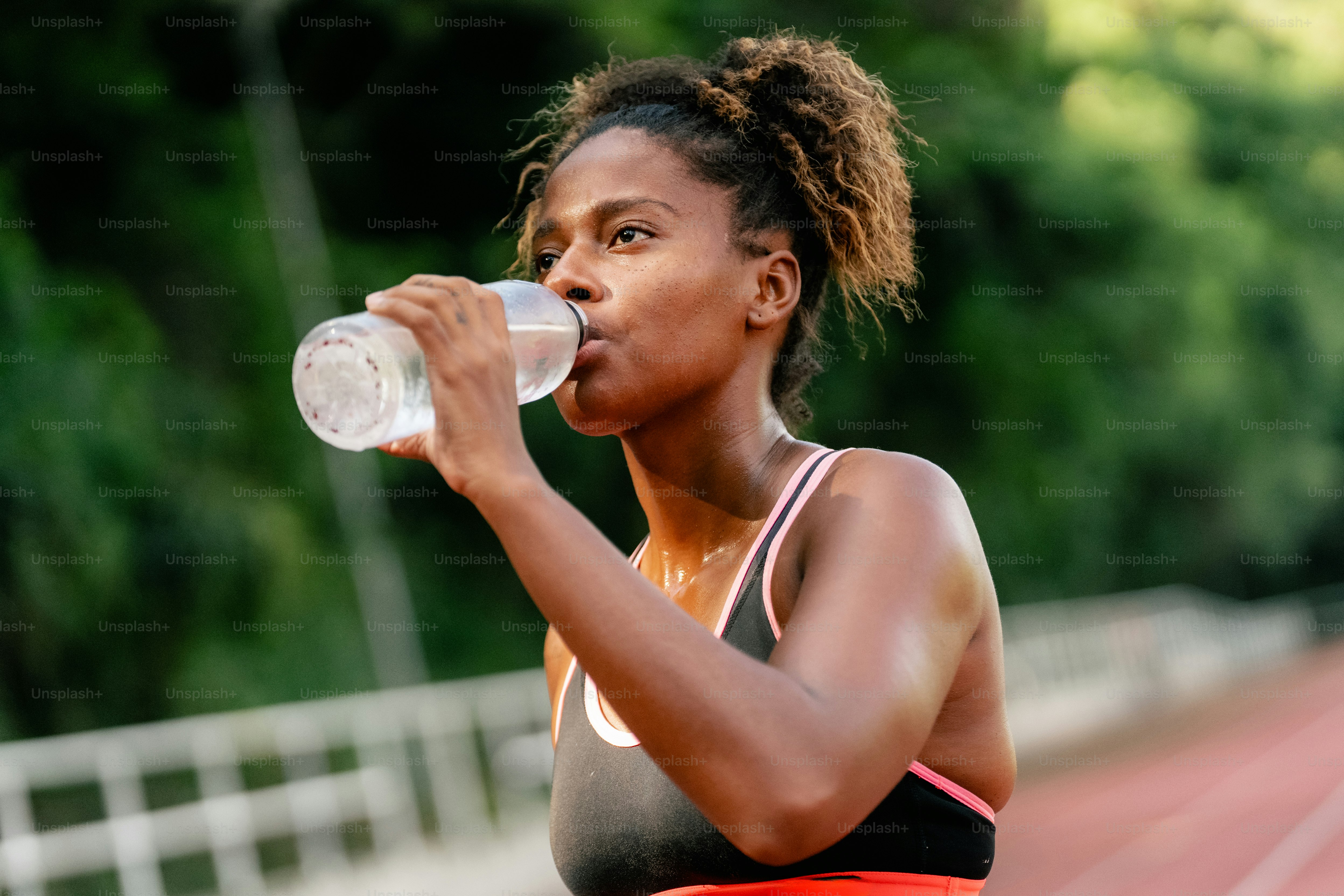 A woman drinking water from a plastic bottle
