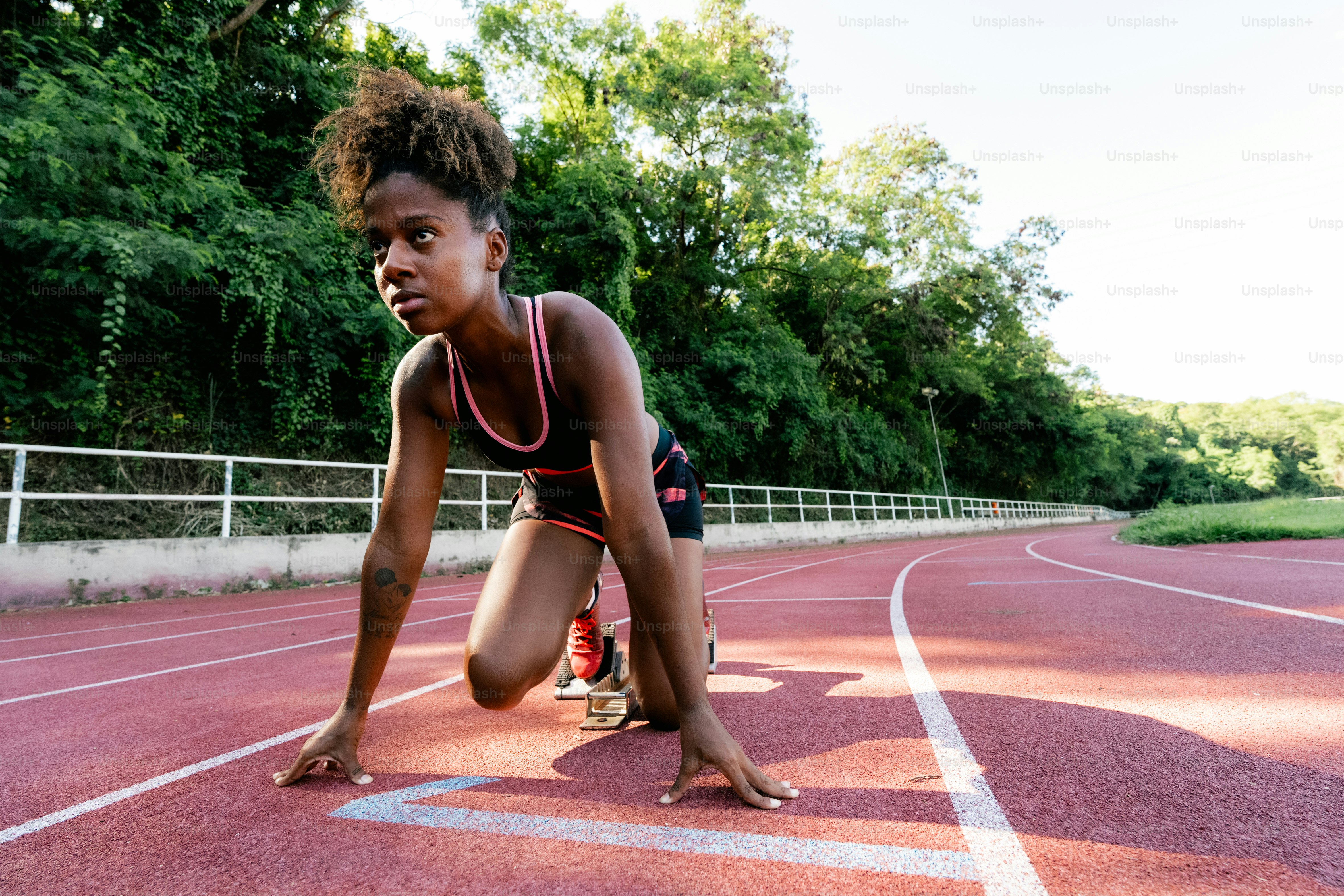 A woman kneeling down on a running track