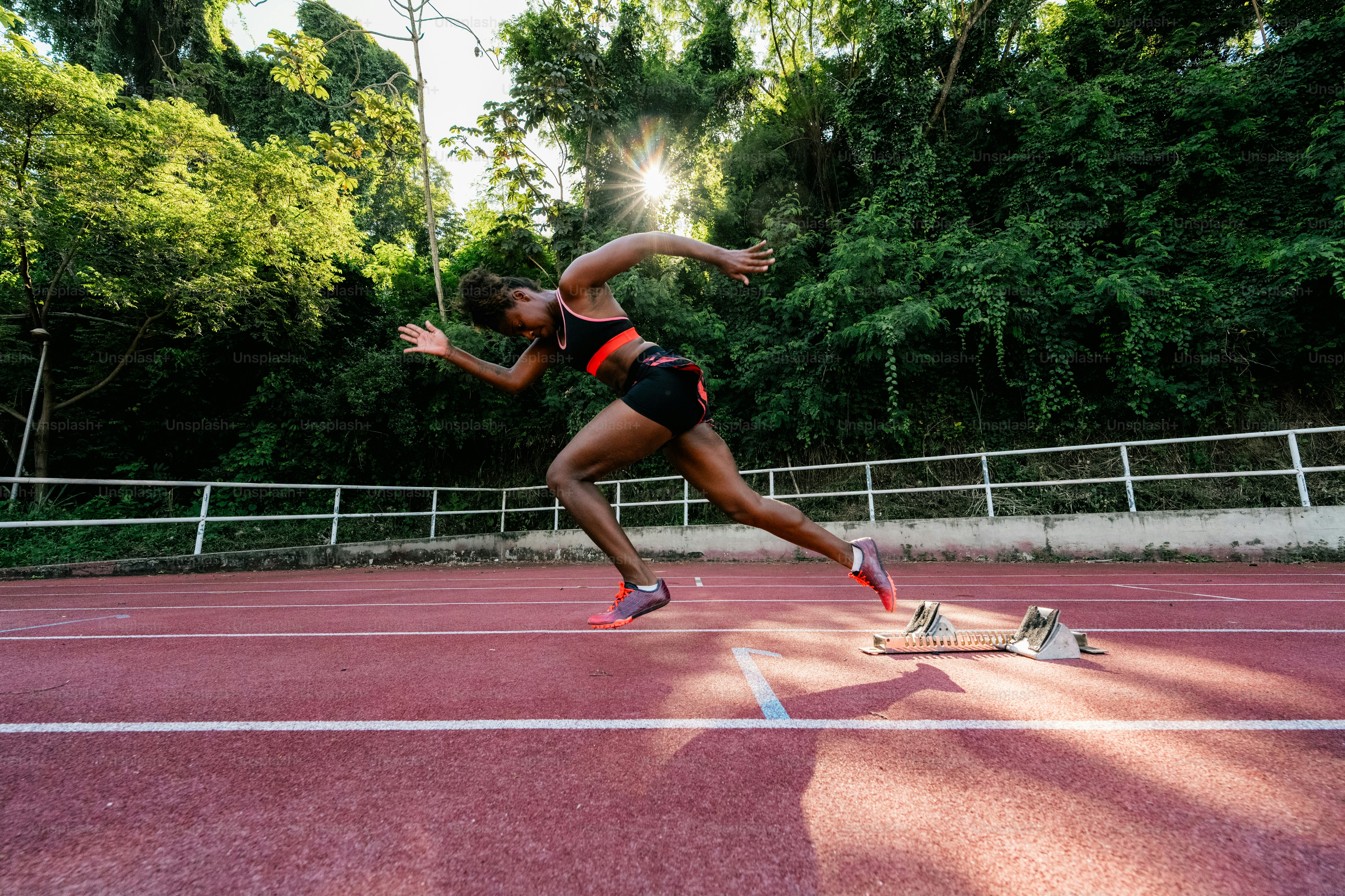 A woman running across a tennis court on a sunny day
