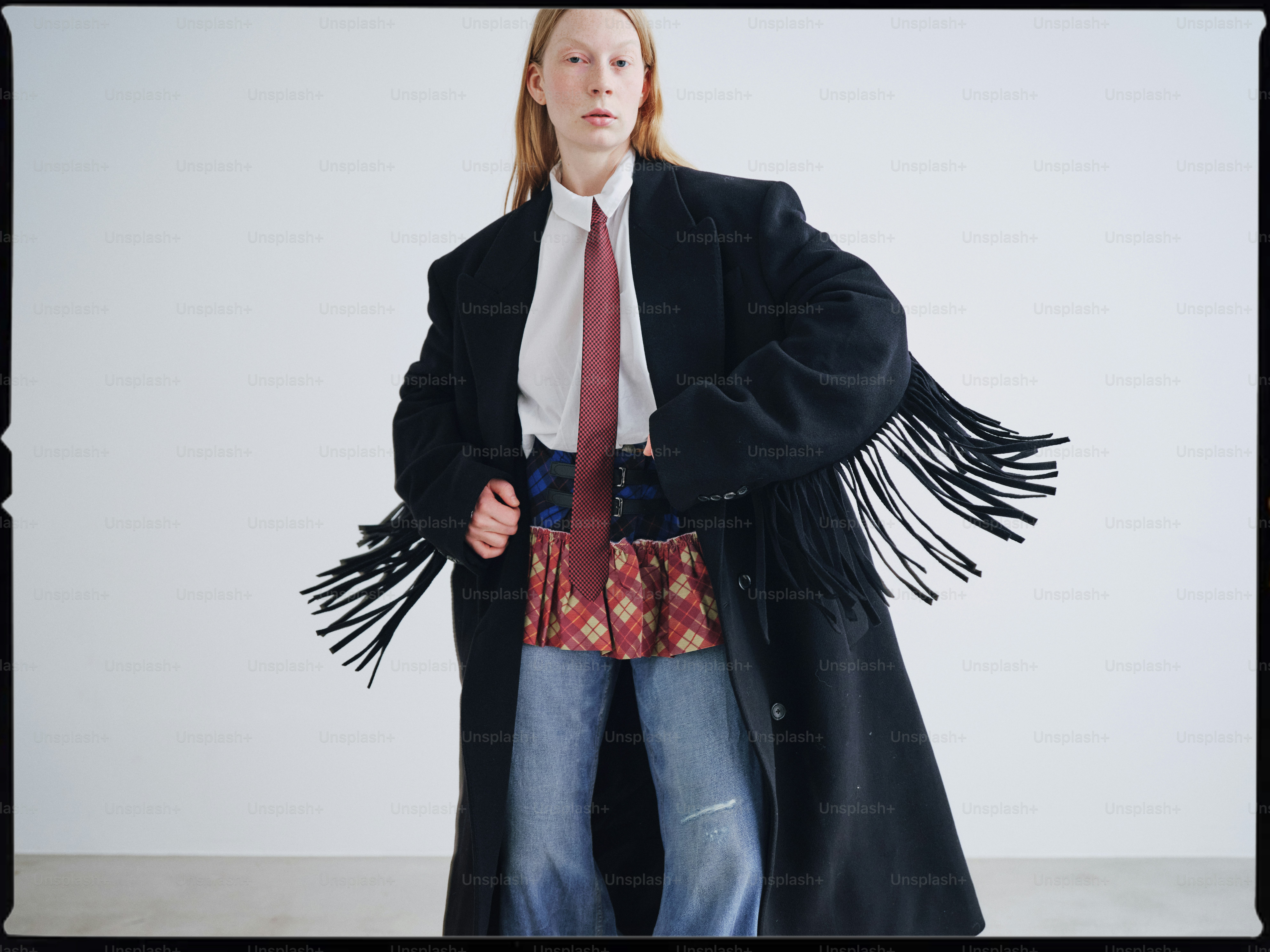 A woman in a long black coat and tie