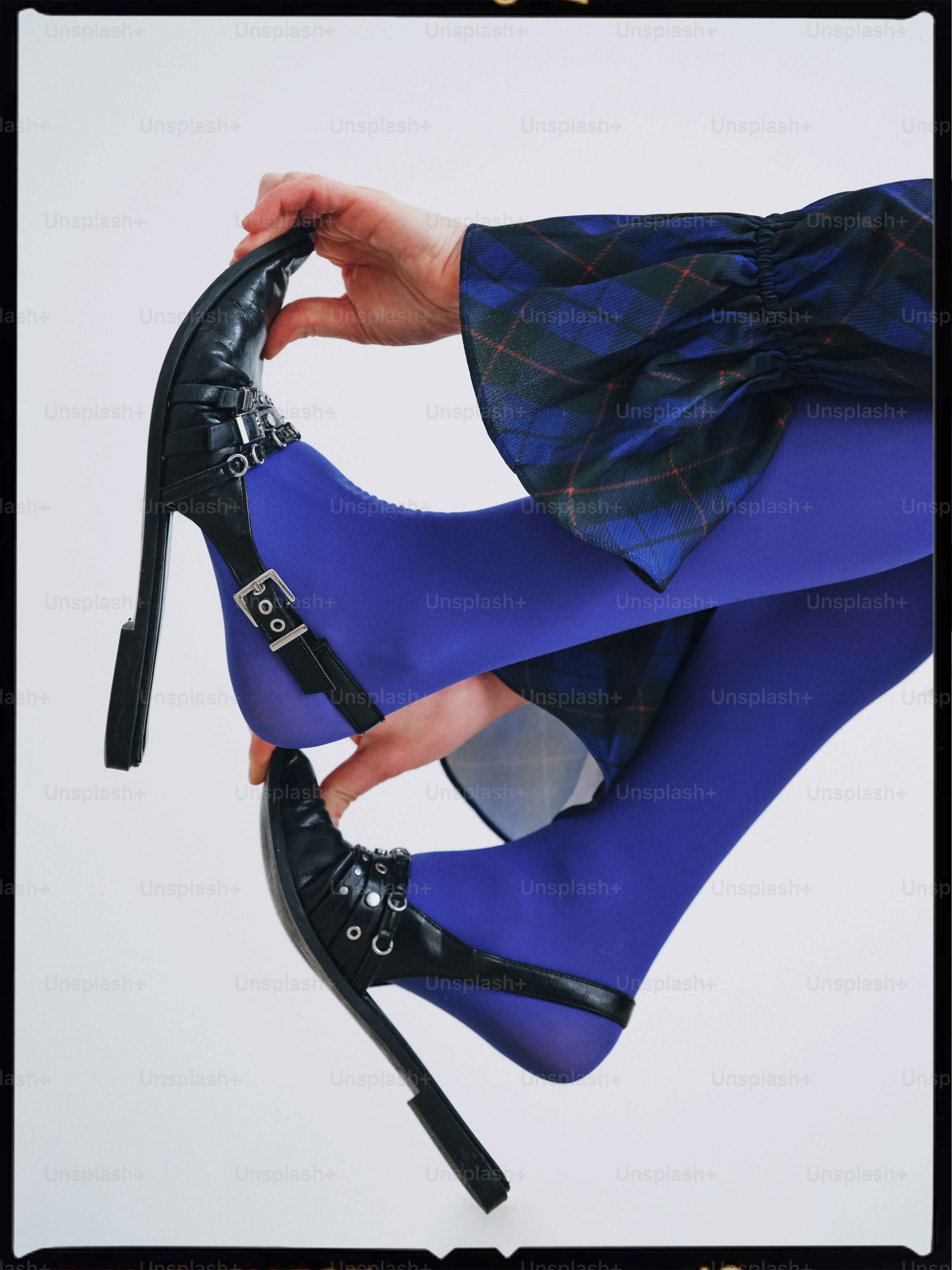 A woman in a blue dress holding a pair of high heeled shoes