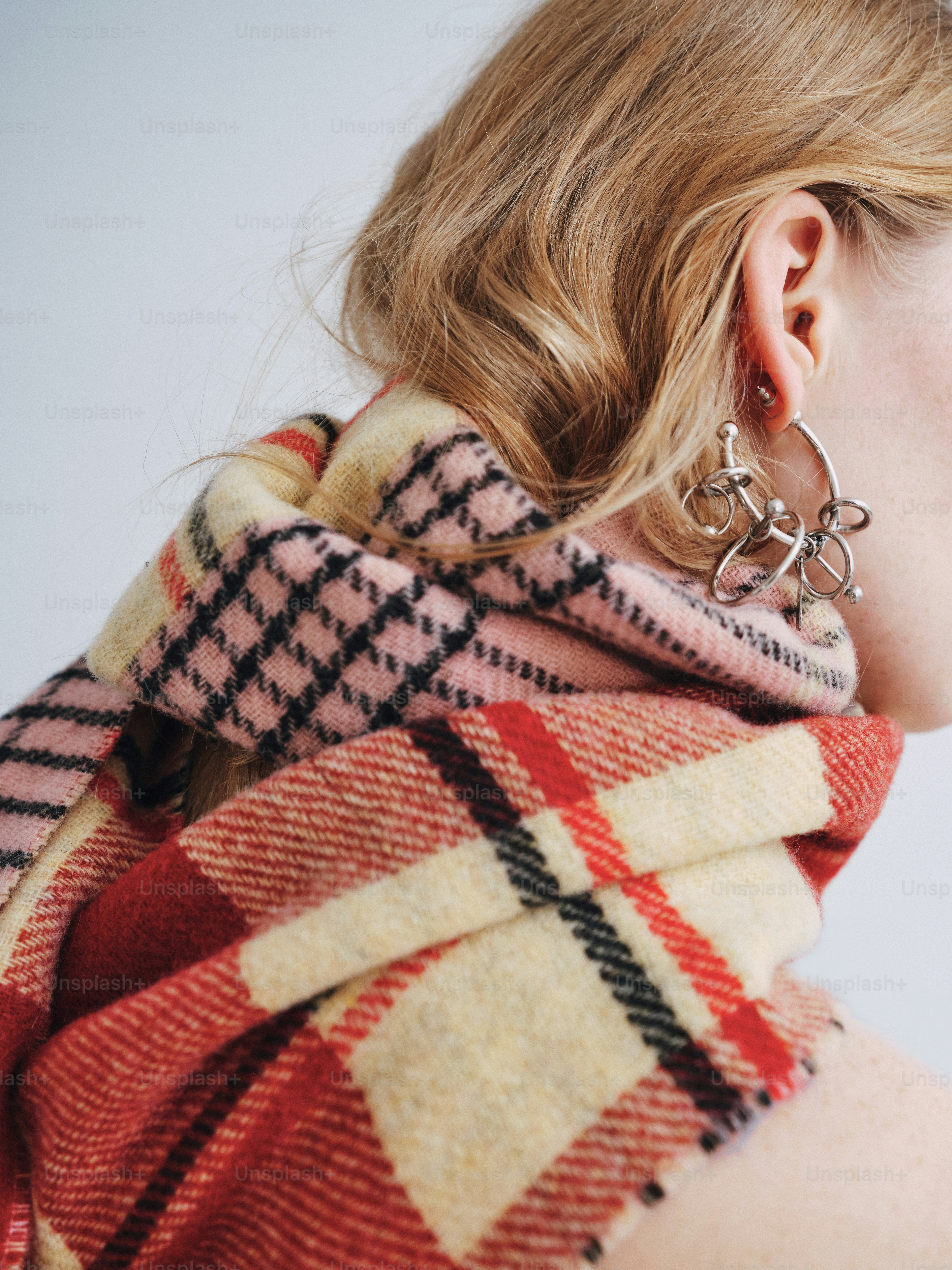 A woman wearing a plaid scarf and earrings