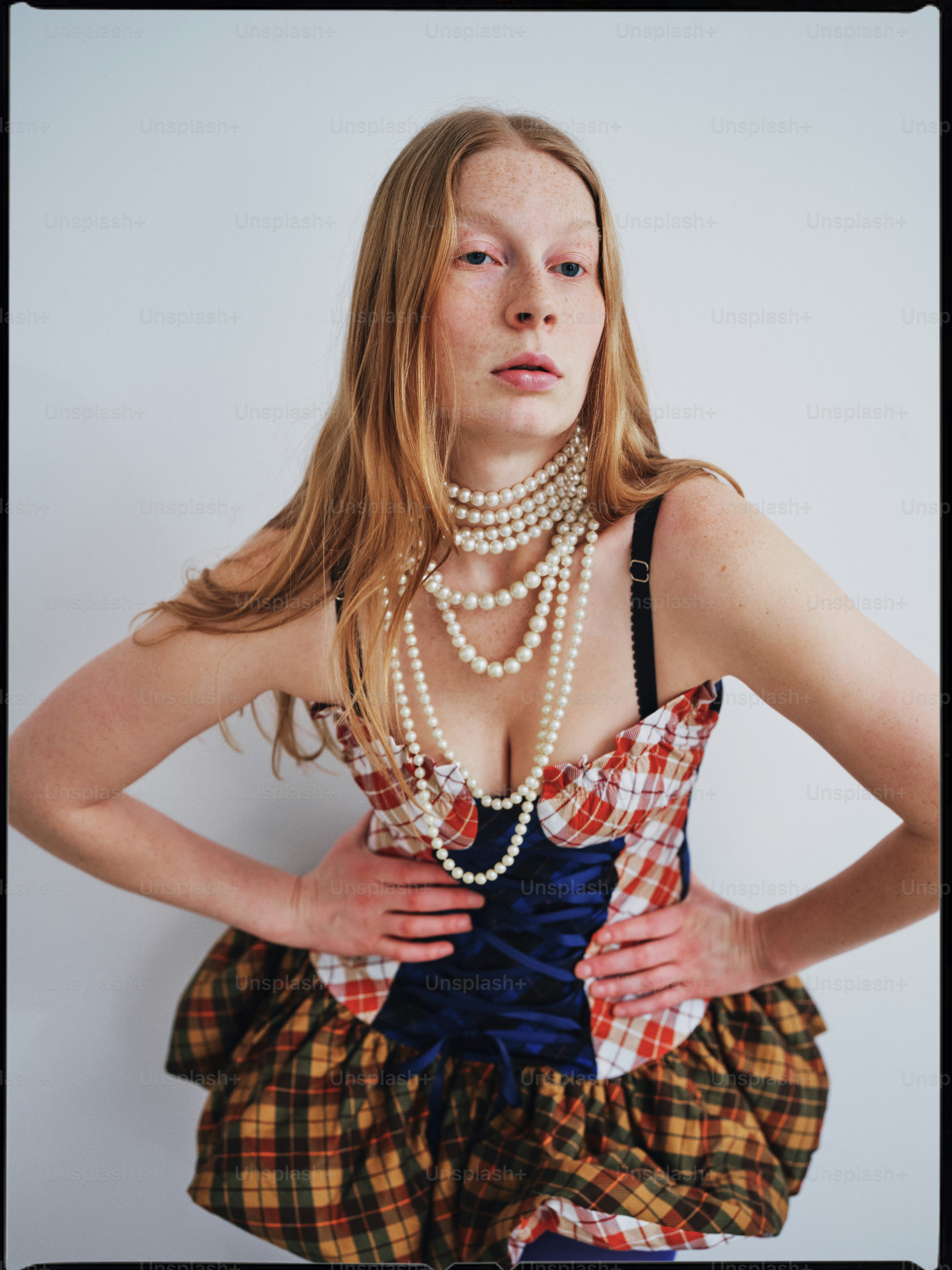 Une femme vêtue d’une robe et de perles pose pour une photo