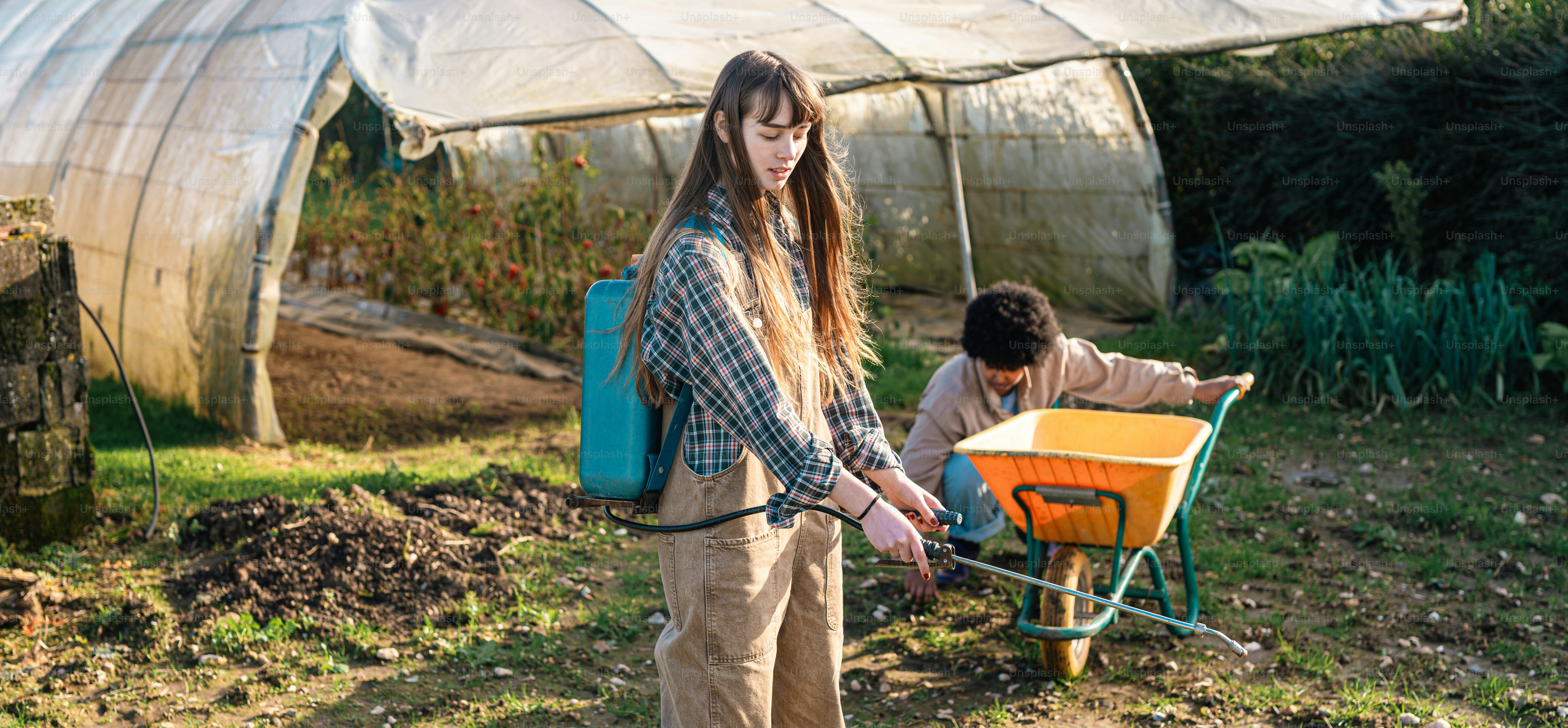 Una donna che spinge una carriola in un giardino