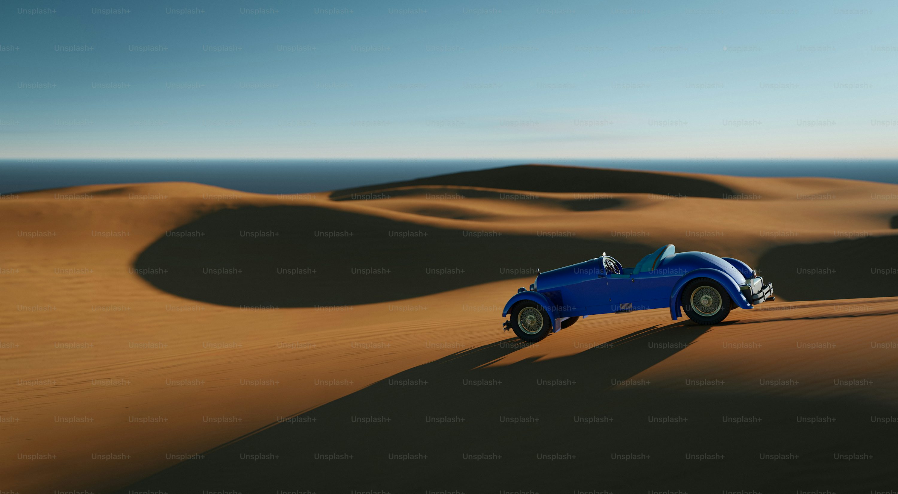 A blue car driving across a desert covered in sand