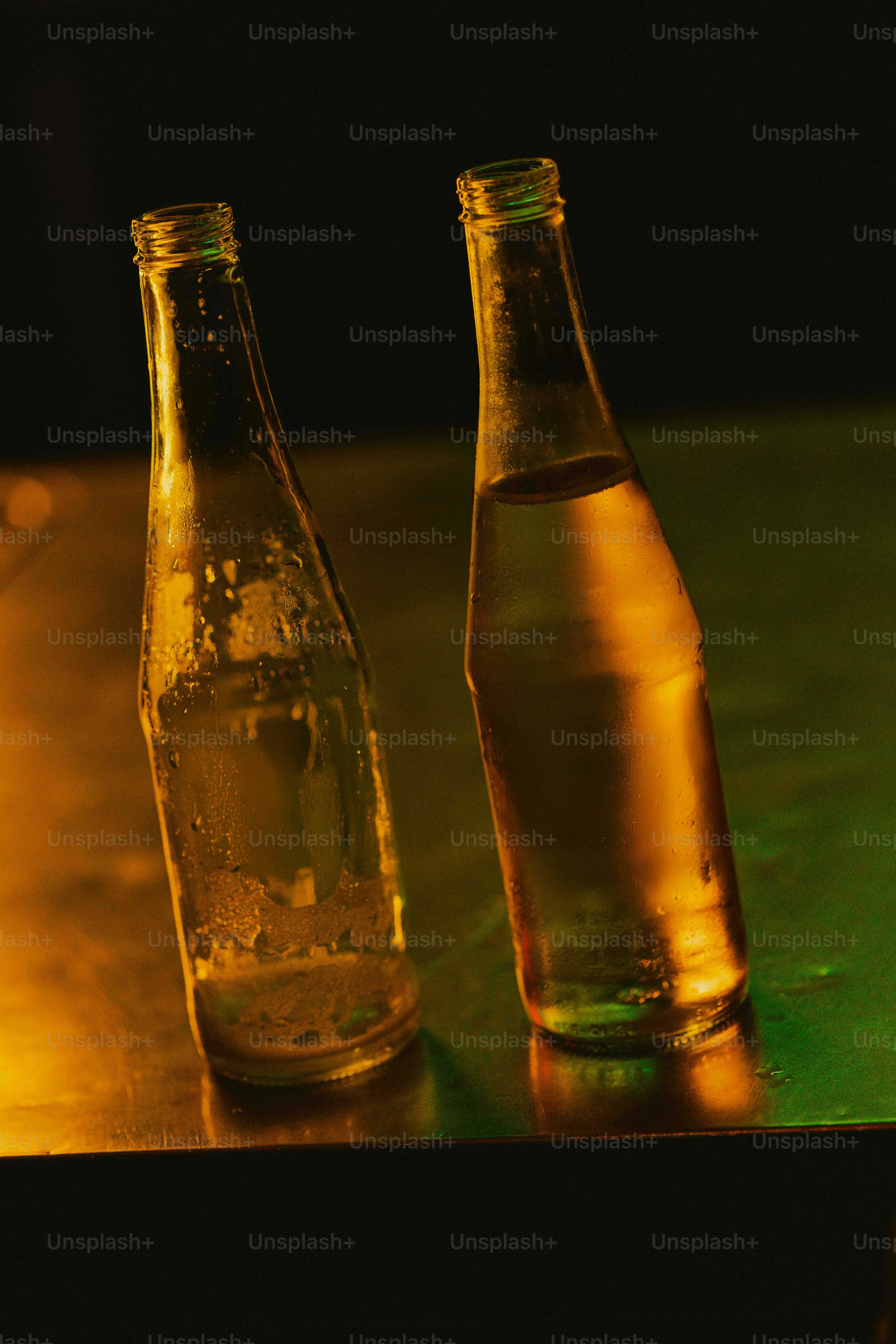 Two empty bottles sitting on a table next to each other photo – Sunset ...