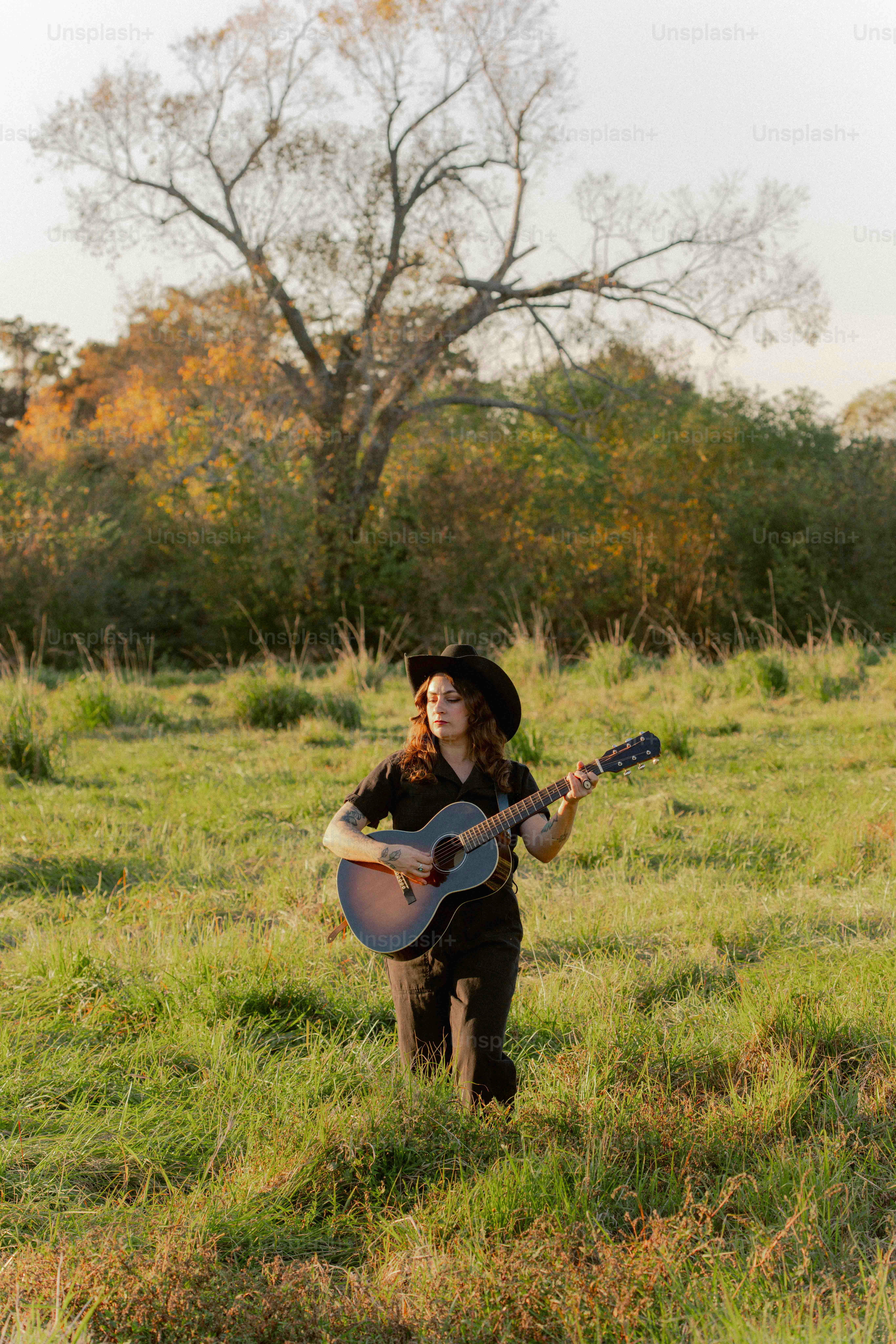 A woman standing in a field holding a guitar