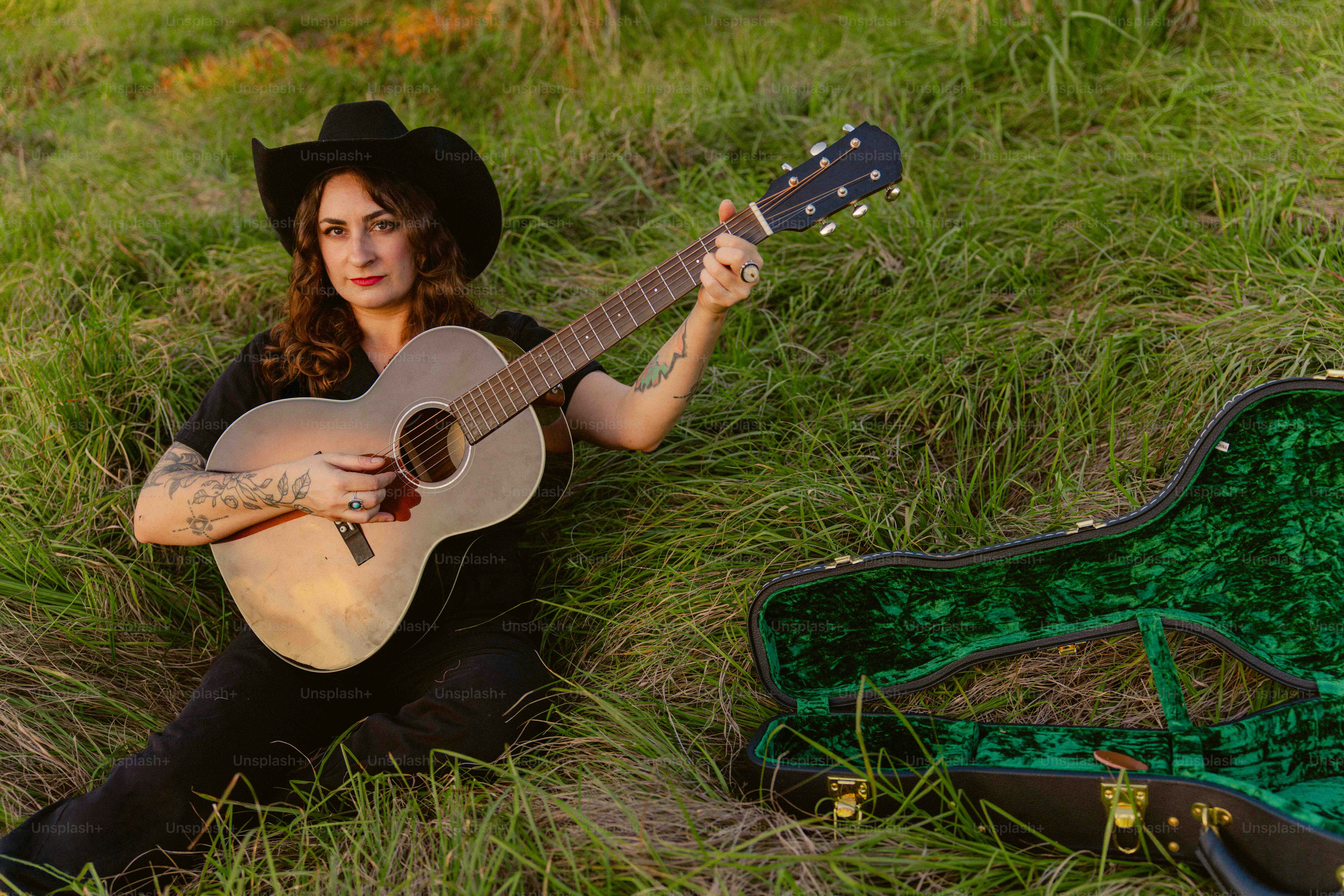 A woman sitting in the grass with a guitar