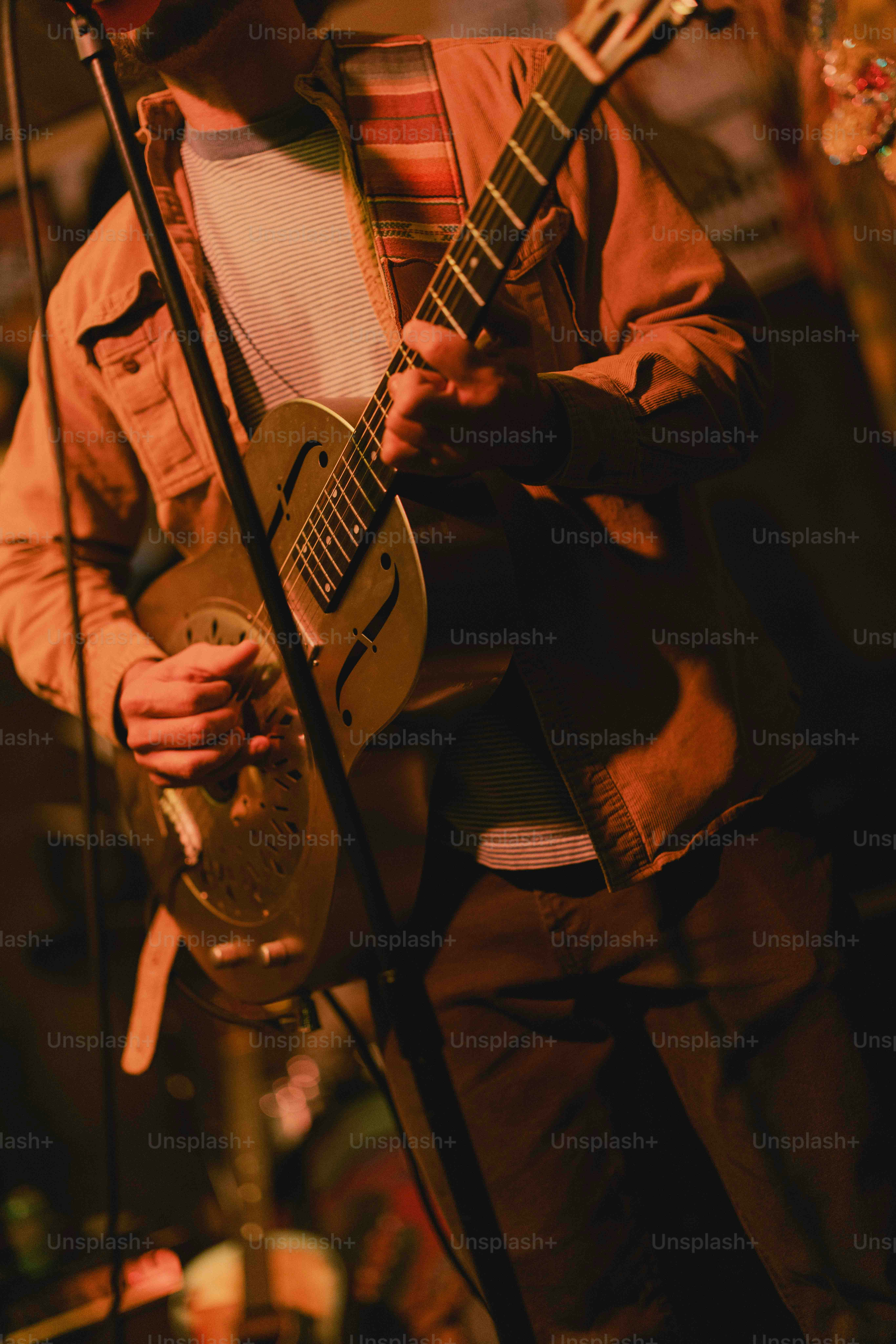 A man playing a guitar in front of a microphone