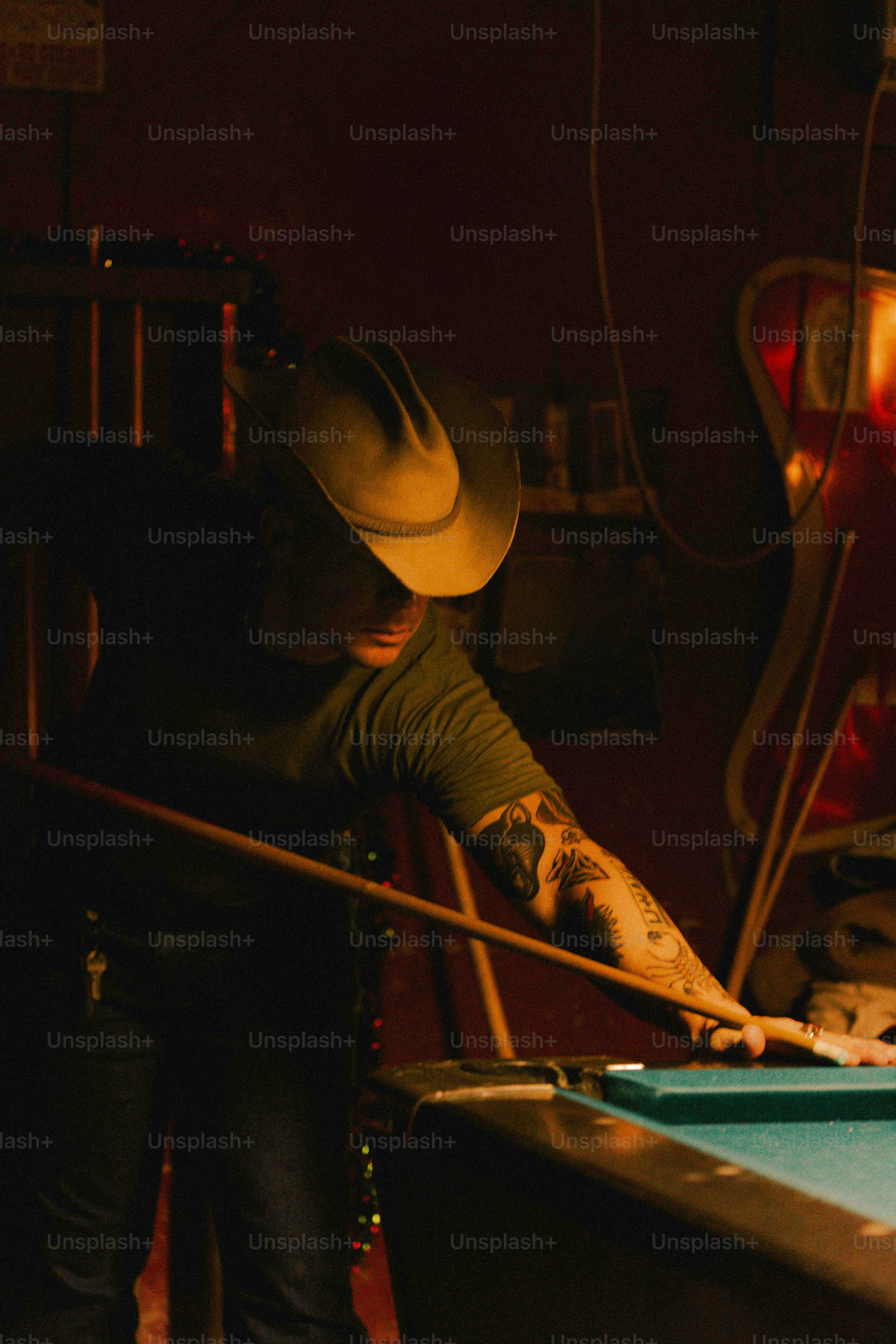 A man in a cowboy hat leaning over a pool table