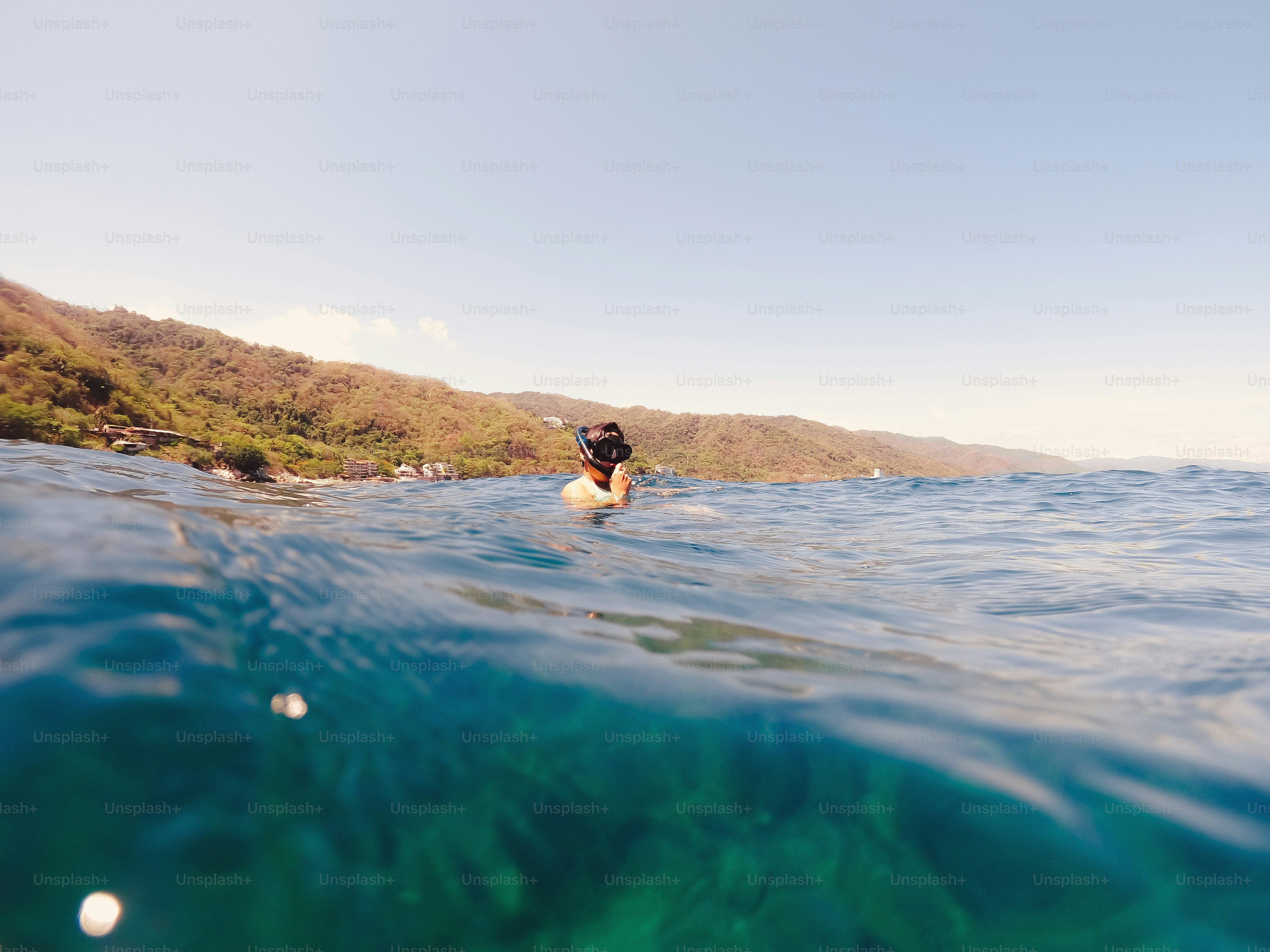 A person swimming in the ocean with a surfboard