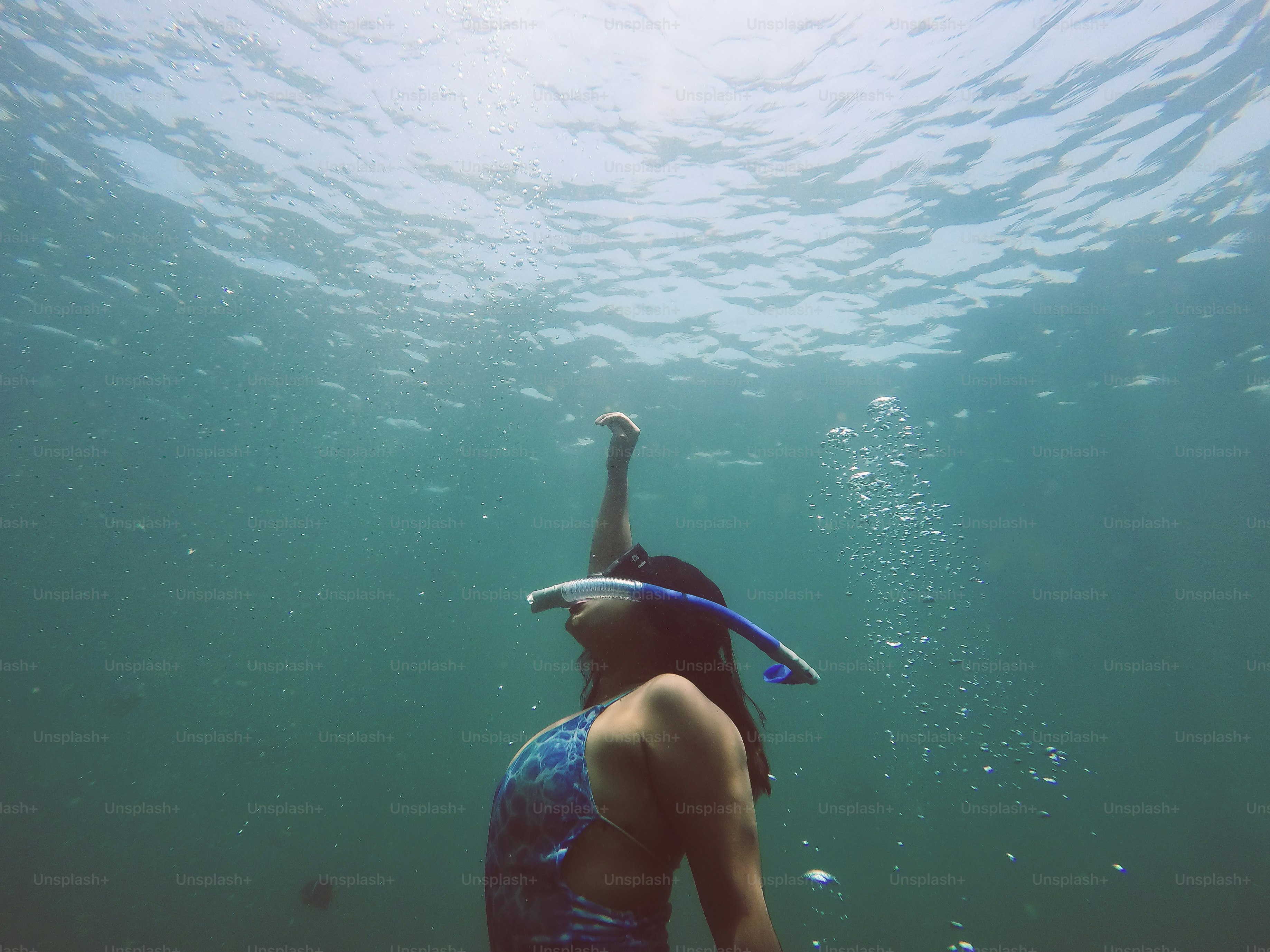 A woman in a blue swimsuit swimming under water