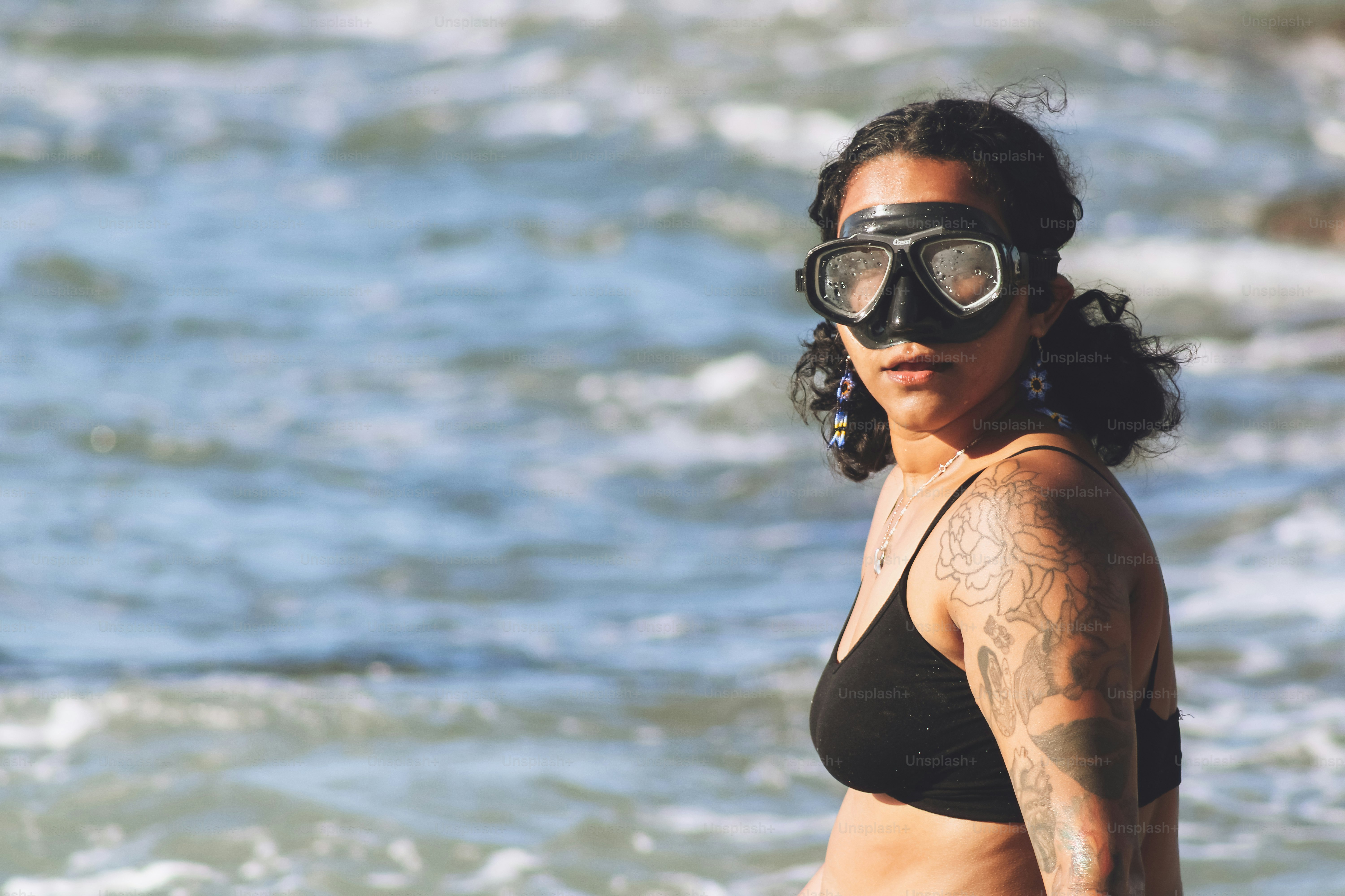 A woman in a bikini and goggles standing in the ocean