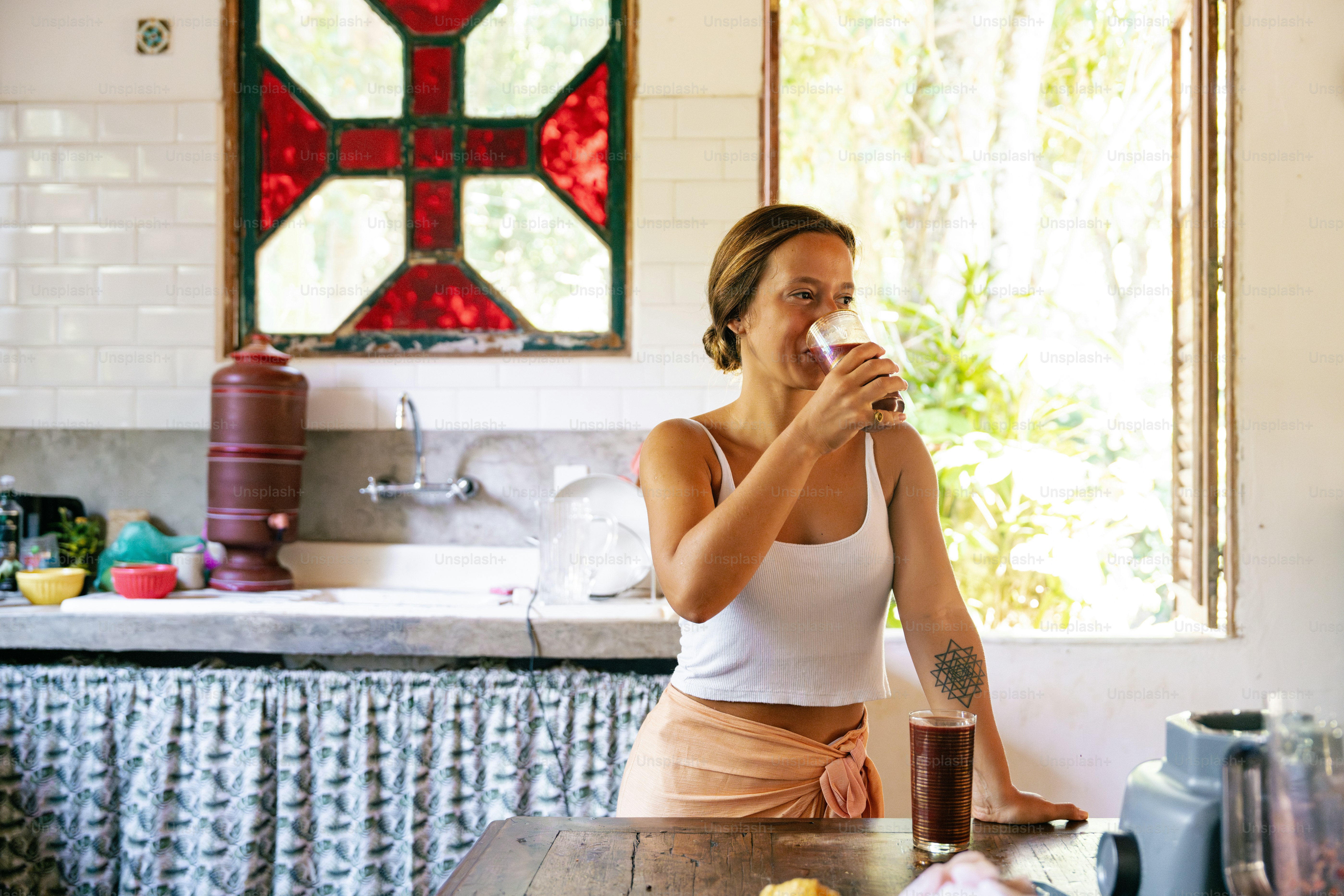 A woman sitting at a table drinking from a glass